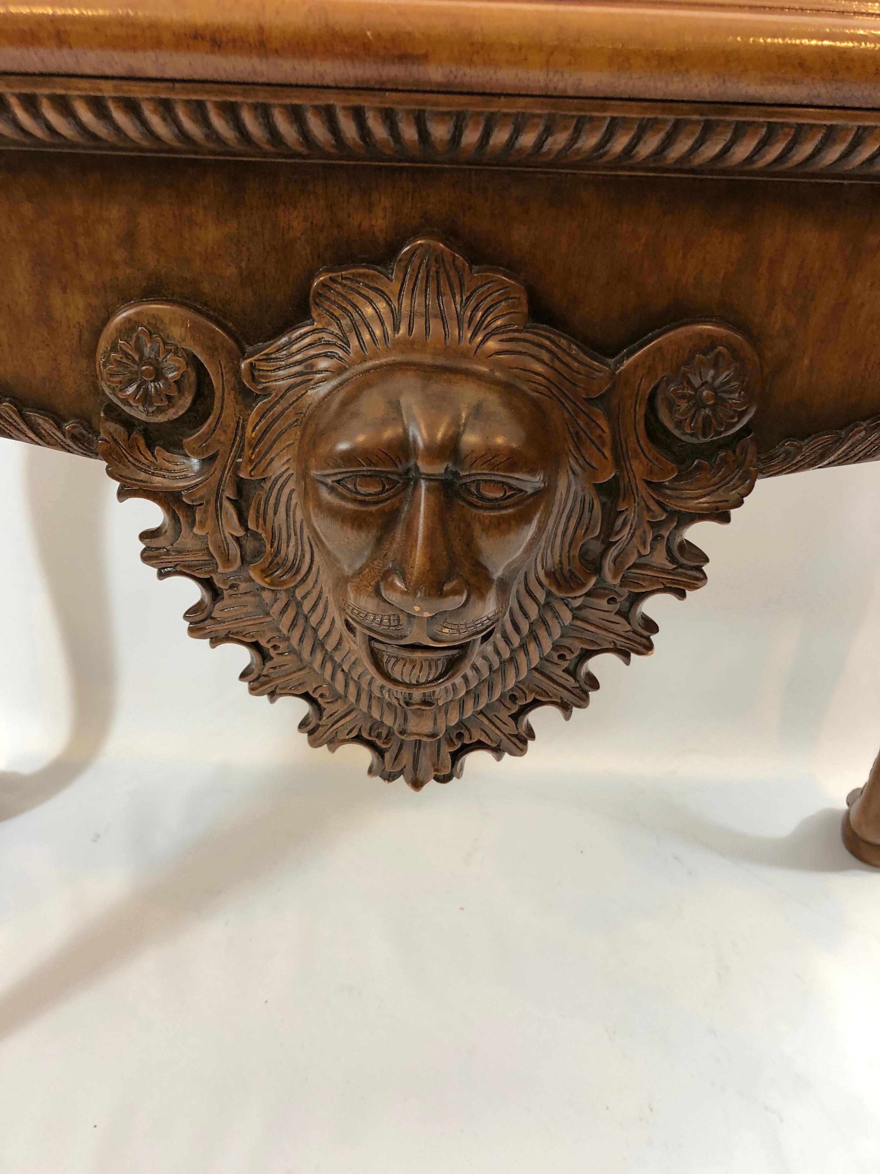 Handsomely designed rich looking console table by Maitland Smith having wonderful carved lions on the front and top of the cabriole legs, as well as a gorgeous tooled leather top with gold border and embossed center medallion. Beautiful from every