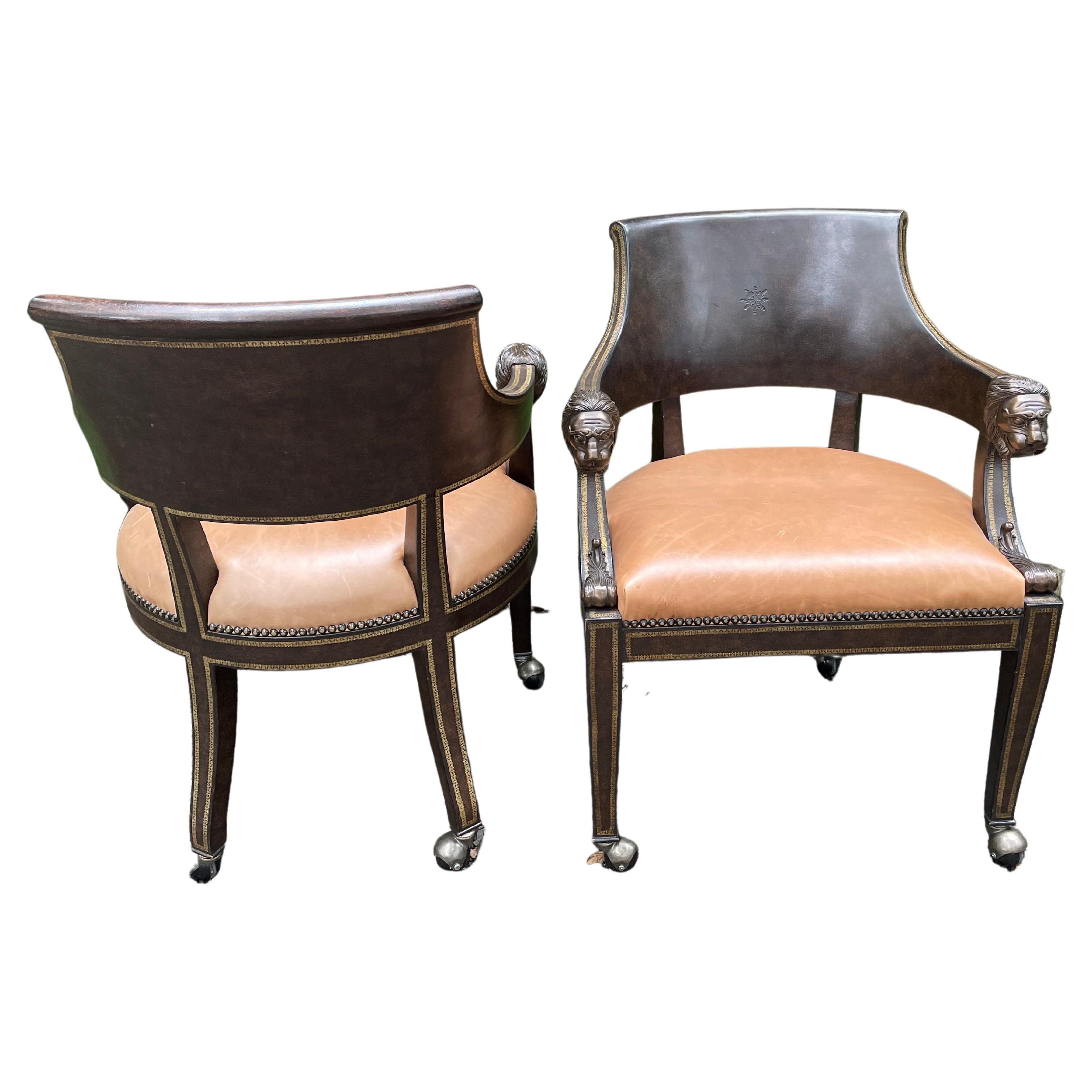 Handsome pair of embossed leather armchairs by Maitland Smith having a straight top rail with bronze cast lion head arm rests on leather back and seat. Nailhead decoration on seats. Chairs have a tooled and gilt apron and legs terminating on casters.