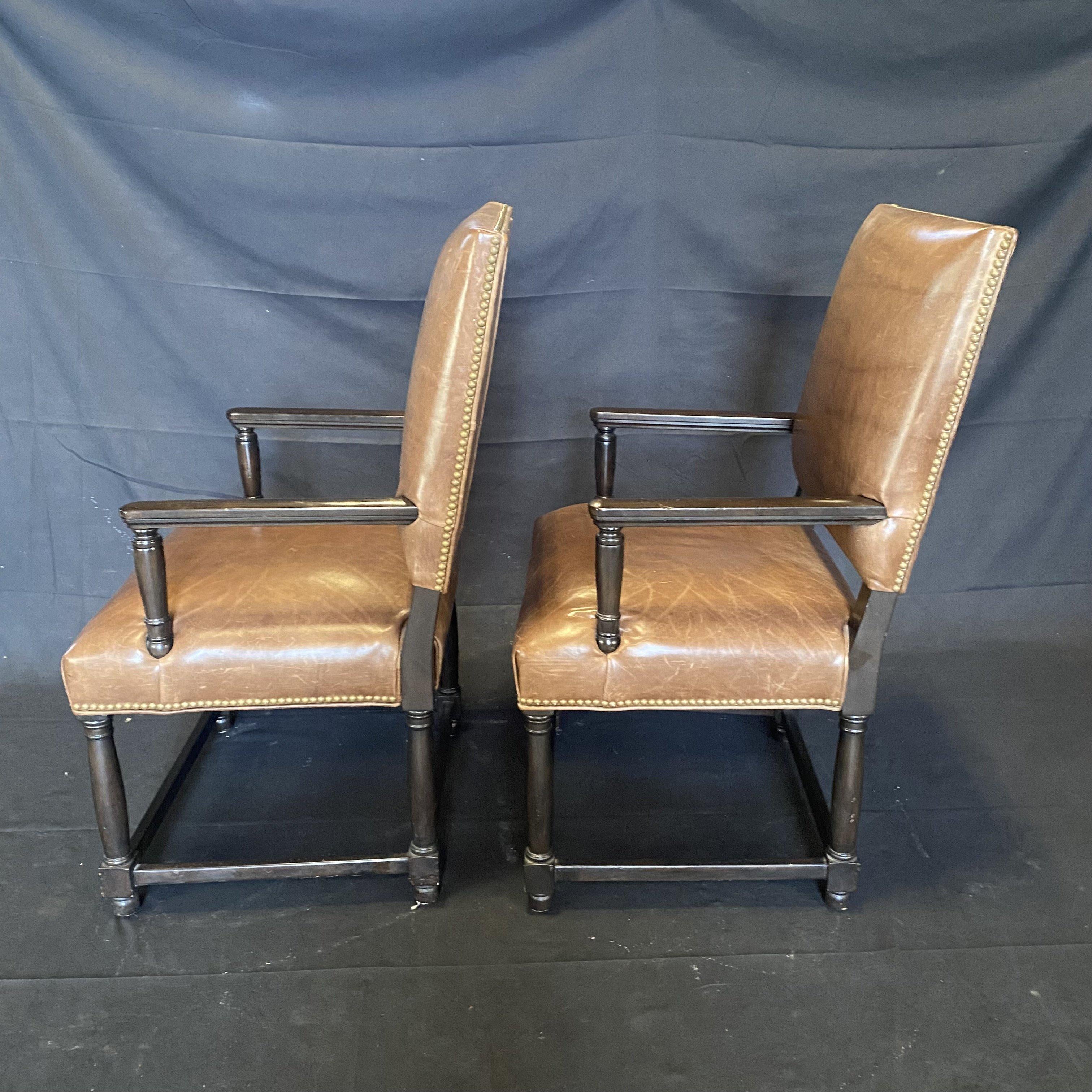 Nice pair of traditional style leather dark wood arm chairs upholstered in tobacco brown leather and finished with brass nailheads.
 Measure: H arm 26.75”.

 