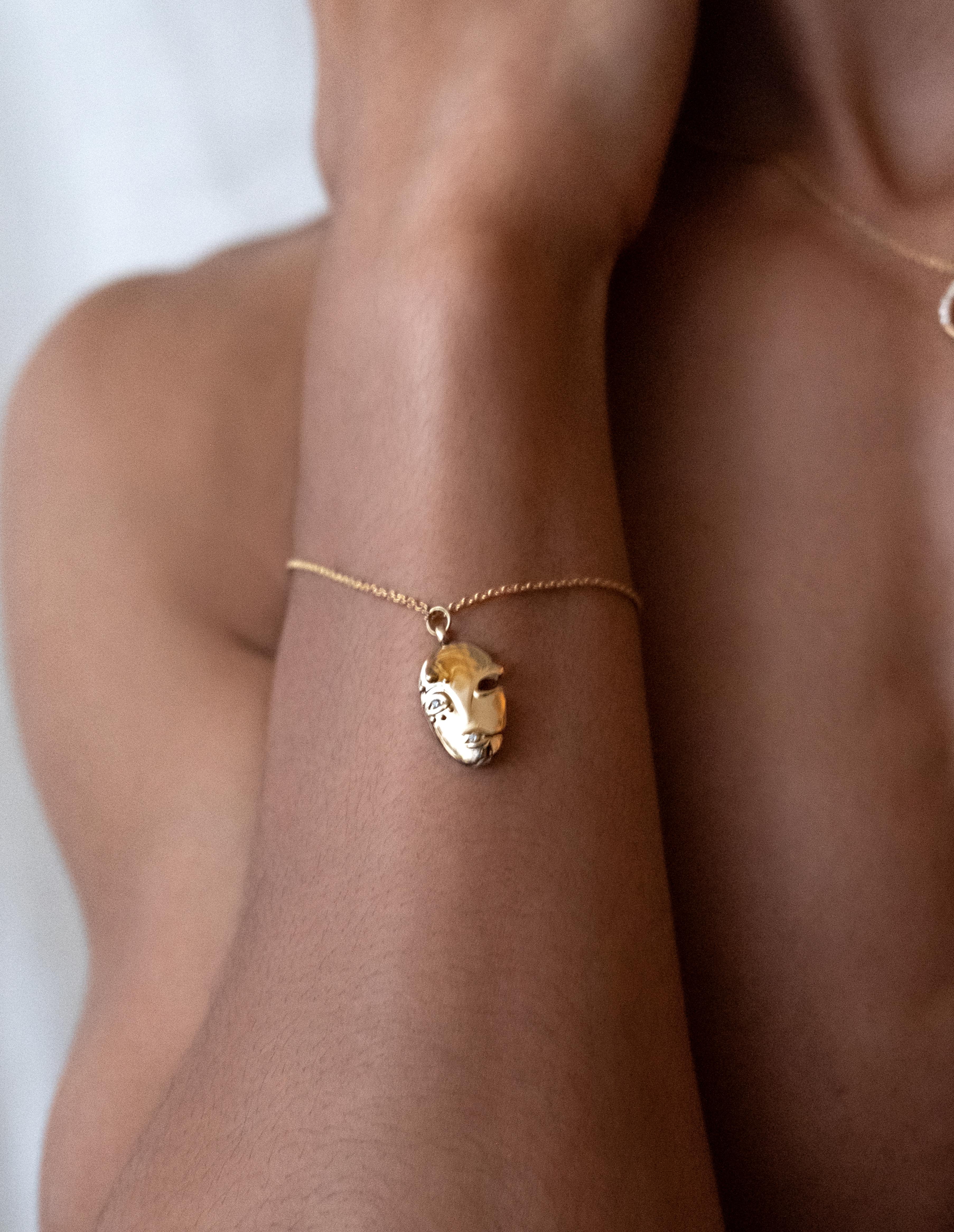 Sculptural Mask Charm Bracelet situating Brancusi’s modernity in conversation with West African sculptural traditions. Rendered in 18K Gold and set with two round cut diamonds. 1.5 inch charm on Adjustable 6 inch total length chain with lobster