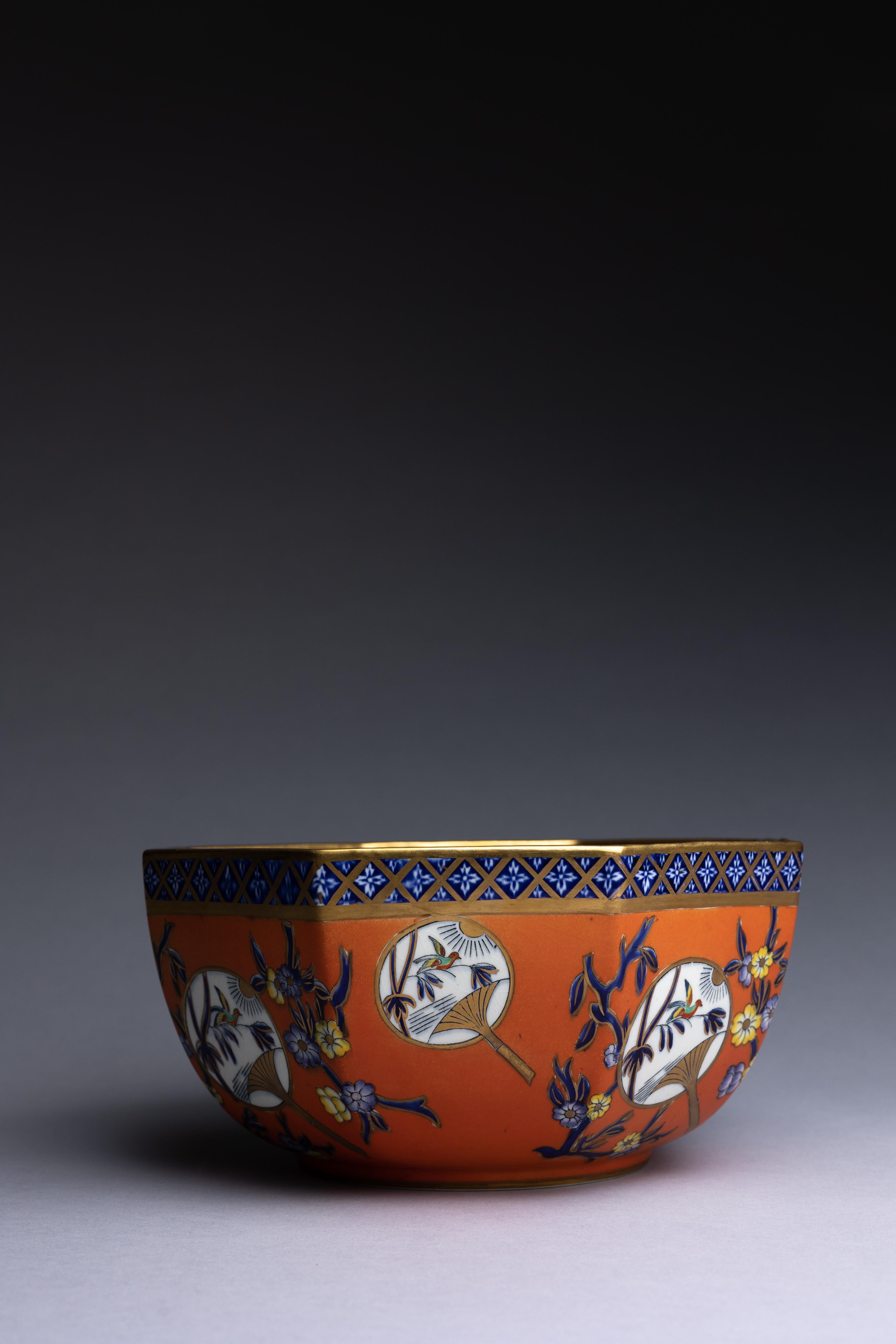 Eine achteckige Eisensteinschale von Mason's Ashworth, verziert mit einer lebhaften orangefarbenen Glasur und zarten Chinoiserie-Details.

Das Design ist im Transferdruck in Unter- und Überglasurblau mit einem Muster aus Vögeln und chinesischen