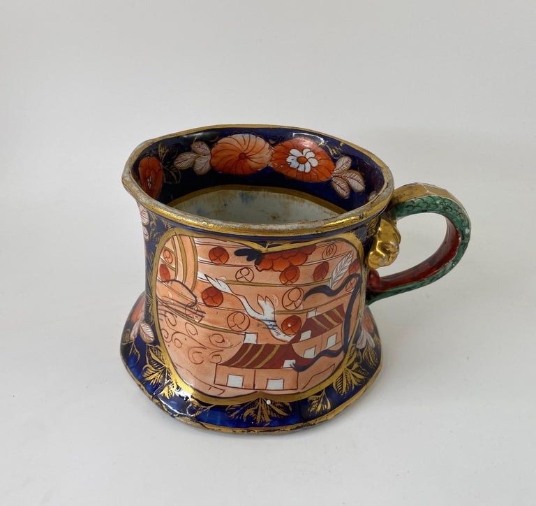 A rare and extremely large Masons Ironstone Quart mug, c. 1815. The huge, faceted mug, with a spreading foot, and vibrantly decorated in the Imari style, with the ‘School House’ pattern, within a gilt panel. The reverse with a panel of flowering