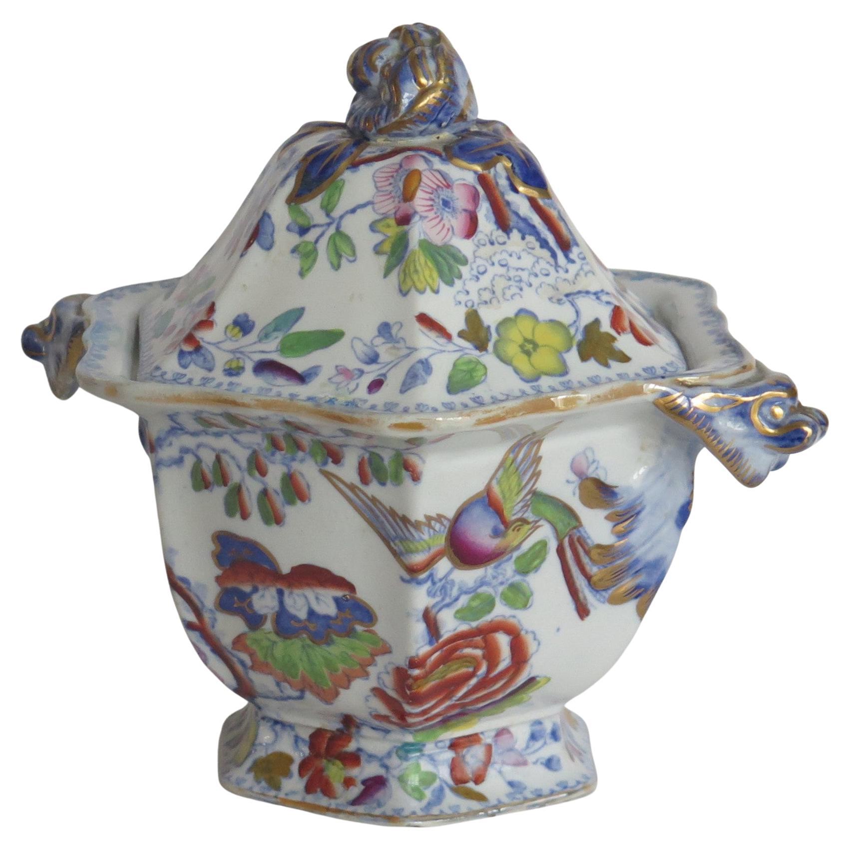 This is an ironstone twin handled Sauce Tureen and Lid, hand enameled & gilded in the Flying Bird pattern, made by Mason's Ironstone of Lane Delph, Staffordshire, England, during the 19th century, circa 1860.

This hexagonal piece is well potted