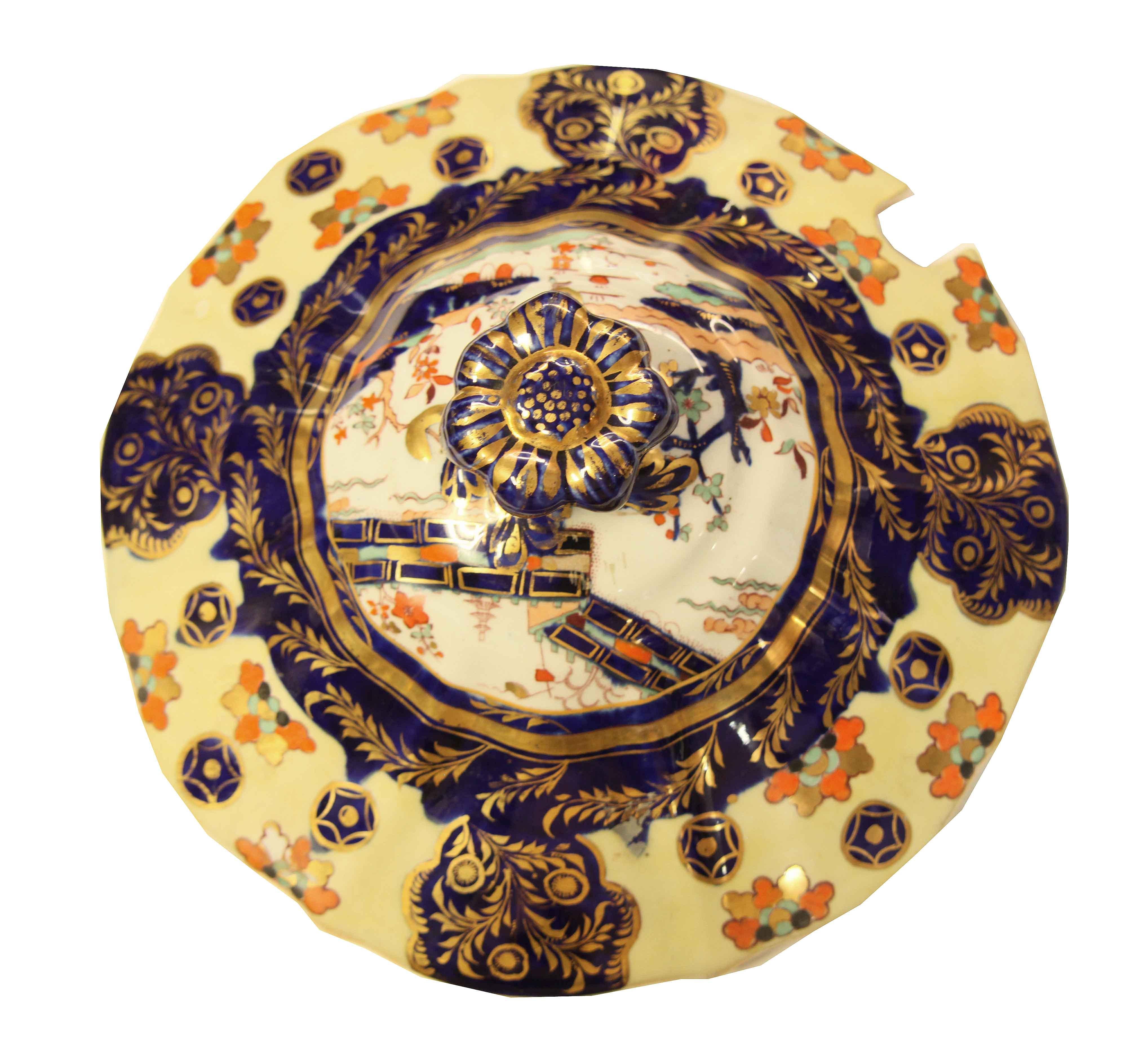 Mason's ironstone tureen and tray, the lid, footed base and under tray all with similar features- a light yellow and white ground color, oriental scenes, intense cobalt blue with gilded foliate,  stylized flowers, and gilded cobalt circles.  All