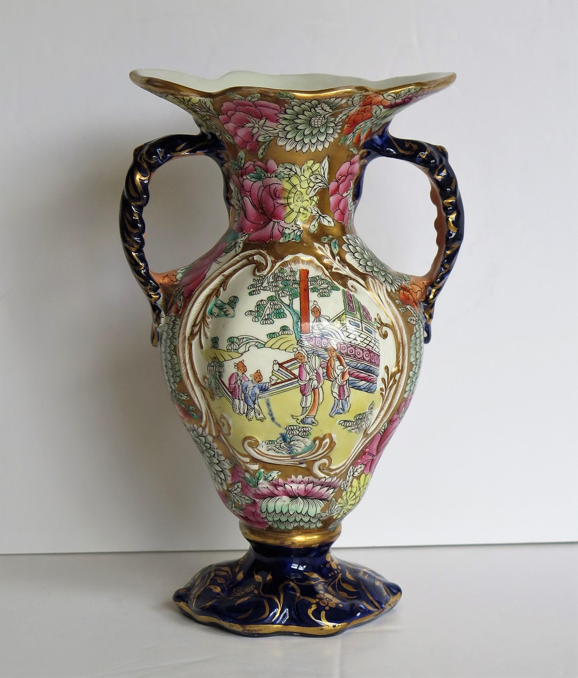 This is a very decorative ironstone twin handled vase made by the English Mason's Ironstone factory, dating to the late Georgian period, circa 1825.

The body is well potted with a hexagonal baluster form, a flaired wavy rim and two loop handles