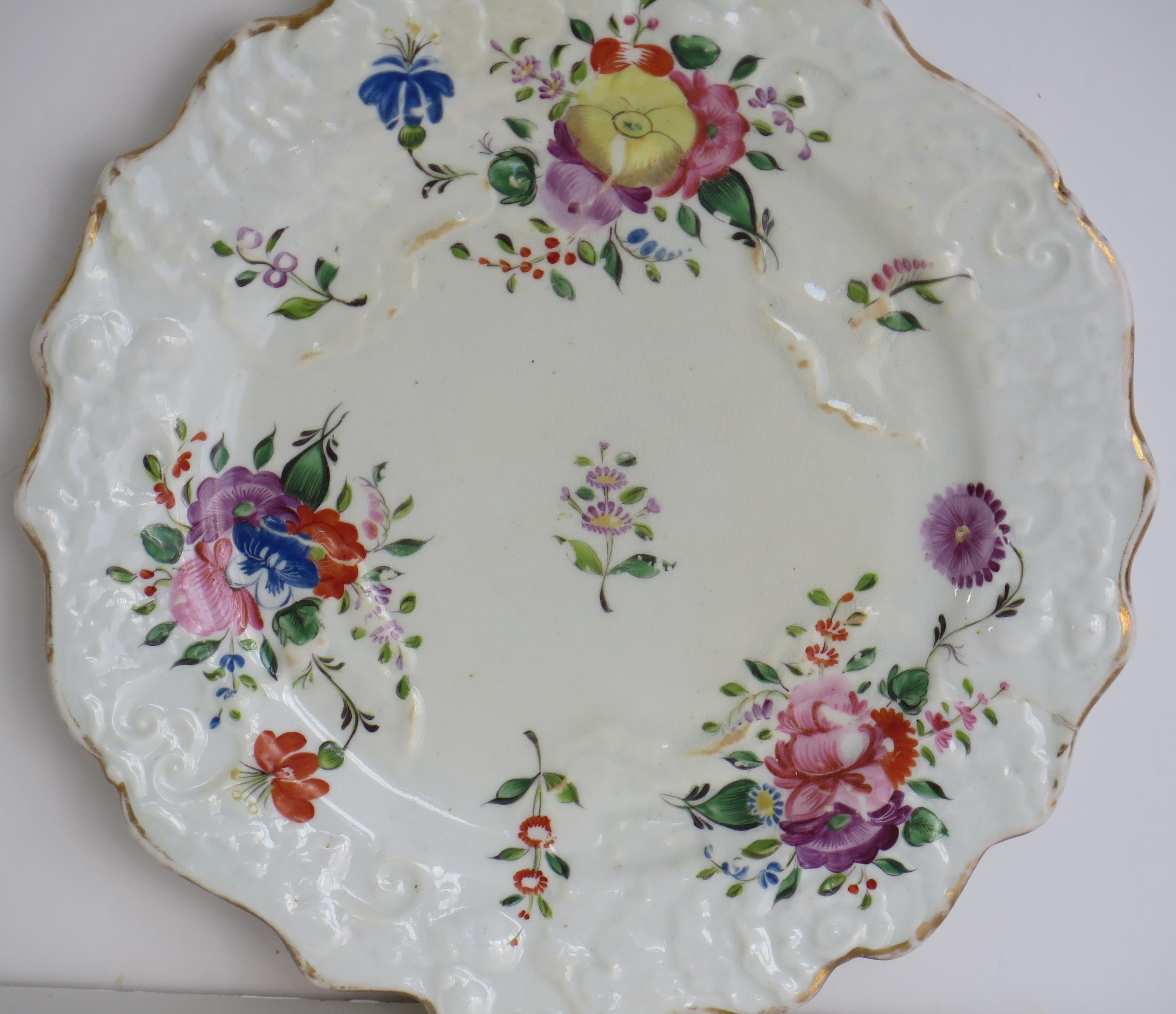 Il s'agit d'une assiette à dessert en porcelaine de Mason's bone china avec un motif peint à la main appelé Central Spray Mixed Border. 

L'assiette a une forme moulée en forme de feuille de chou. 

Il s'agit d'un magnifique motif floral peint à