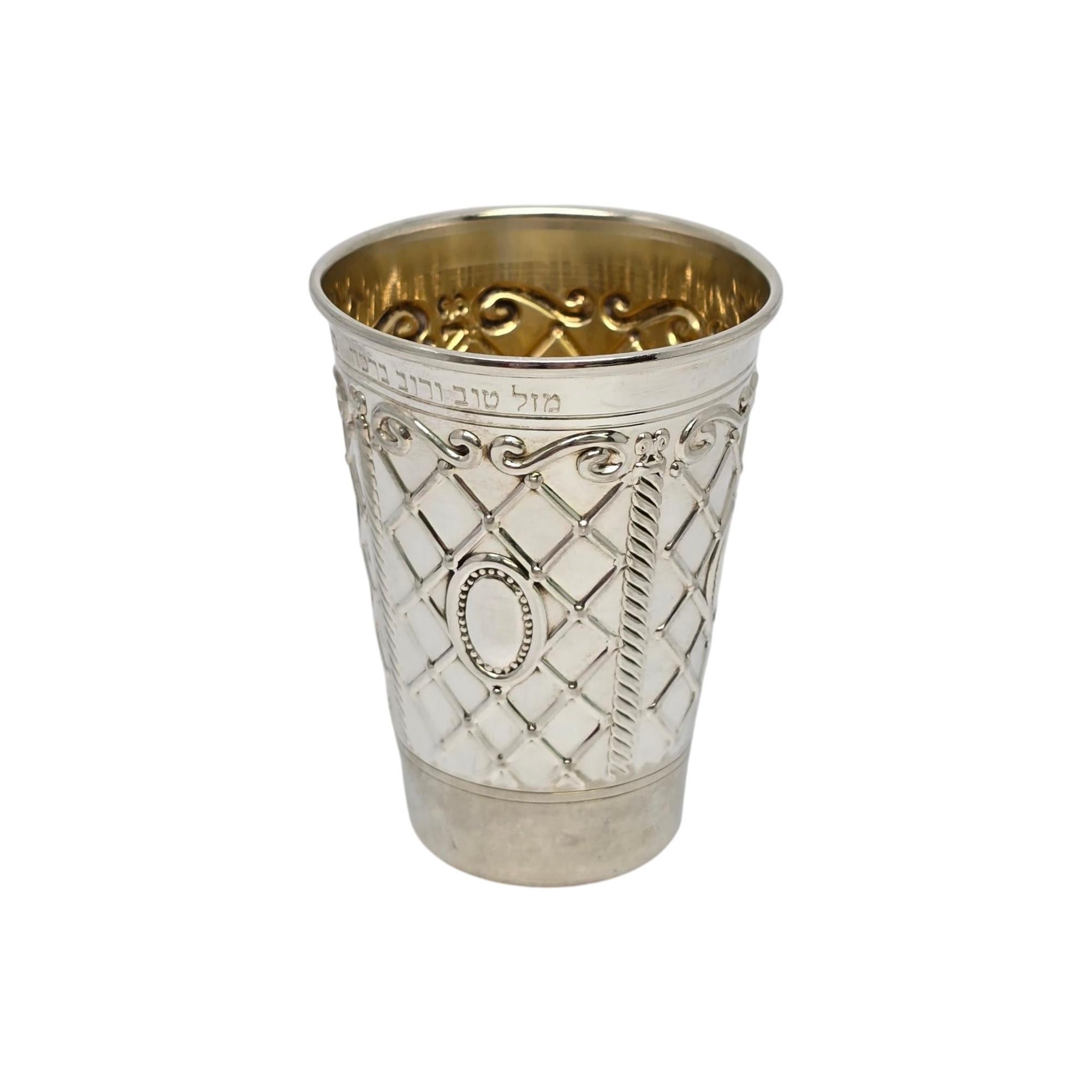 Sterling silver kiddush cup with gold wash interior by Masorett, with engraving.

Engraved with Hebrew inscription (see photos).

This beautiful kiddush cup features a checkerboard and scroll pattern with gold wash interior.

Measures approx 3 1/4