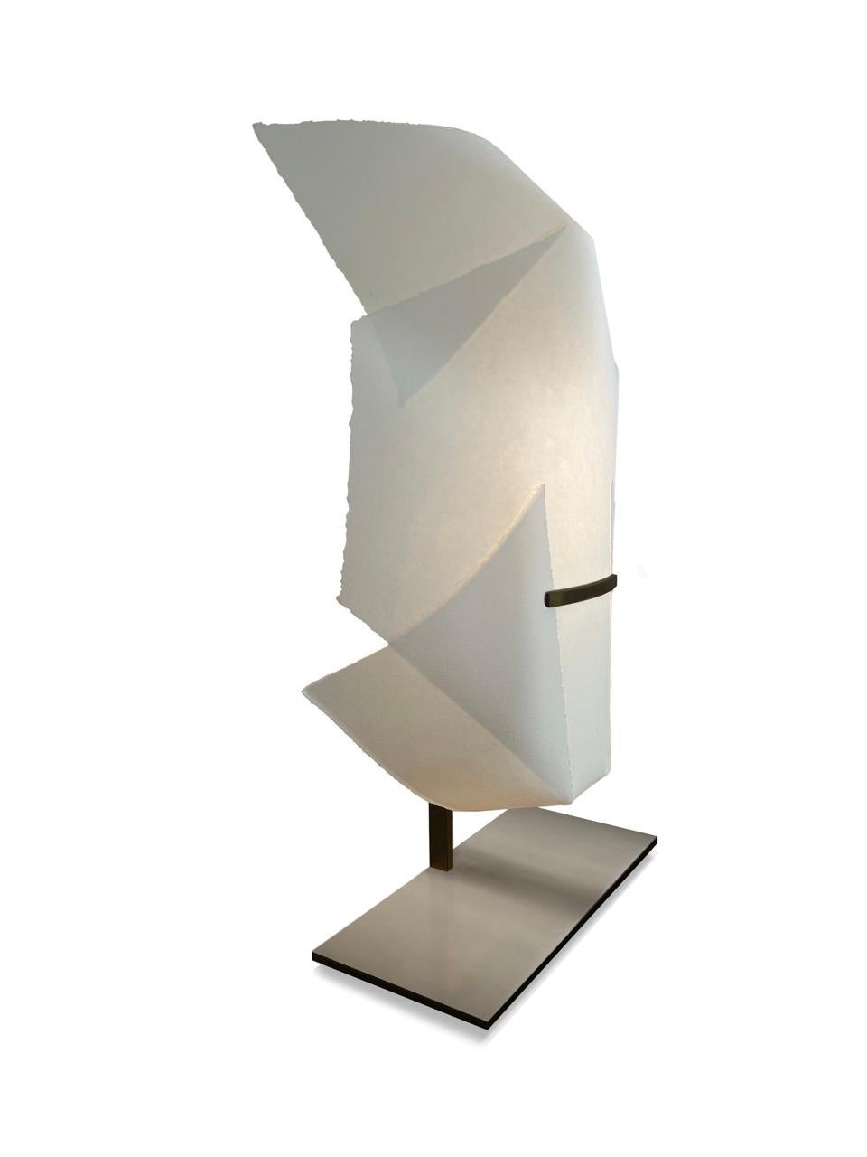 lámpara de mesa masque

En 2024, Charlotte Besson-Oberlin, maestra en el arte de jugar con los volúmenes, fabricó una lámpara Masque de papel de algodón y pátina esfumada semi-industrial, de una presencia y una ligereza sorprendentes. El papel se