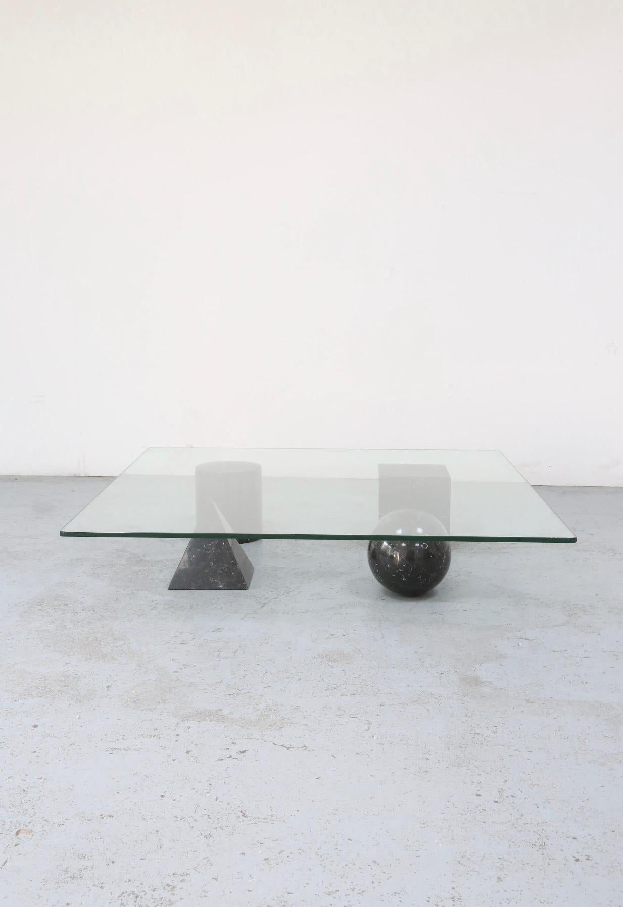 A Massimo Vignelli & Lella Vignell “Metafora” coffee table featuring four black marble geometric shapes and a square 1/2” thick glass top. Each of the geometric shapes can be assembled into different configurations at will. The table was