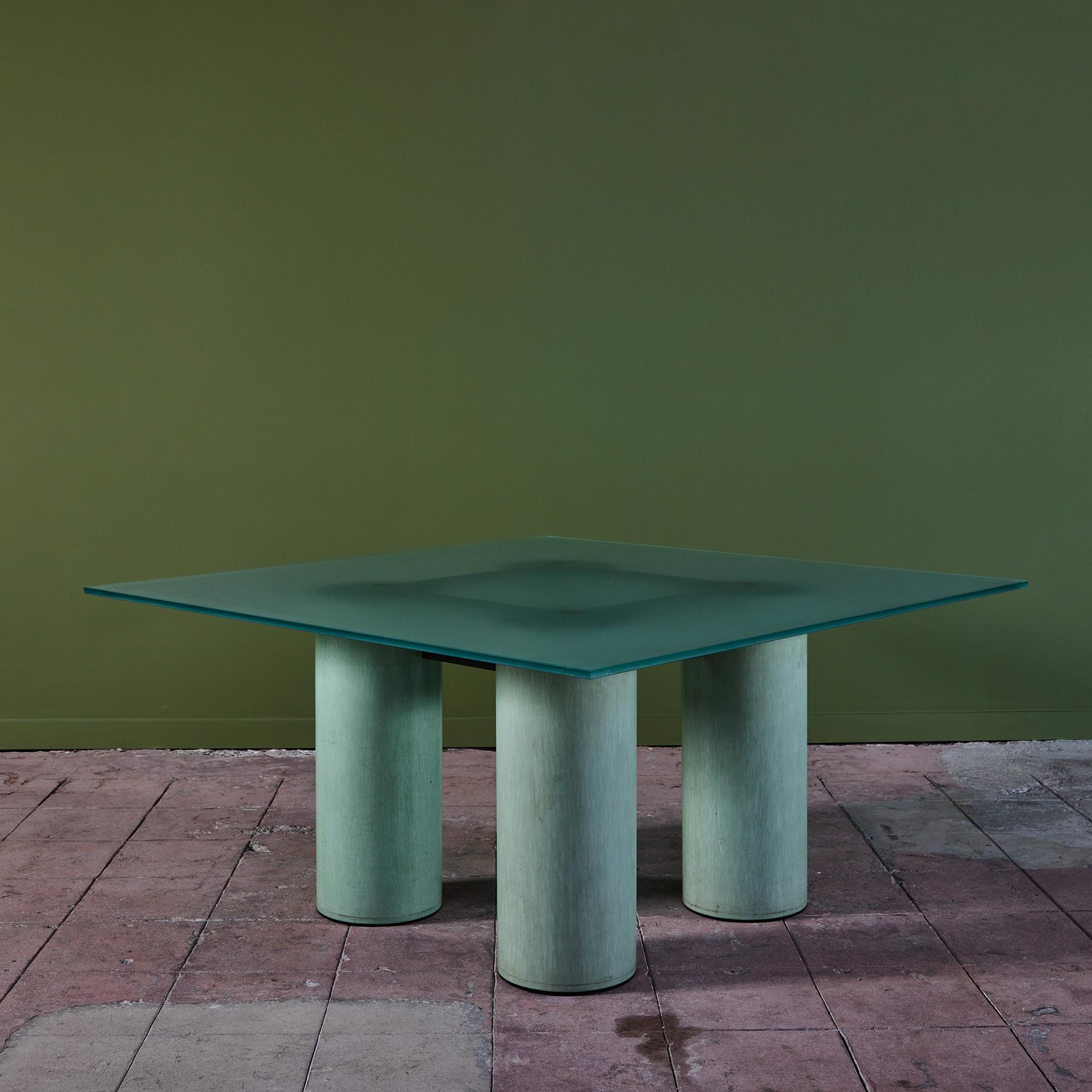 Dining table by husband and wife design duo Massimo and Lella Vignelli and David Law for Acerbis, Italy, c.1980s. The square dining table features a frosted glass table top and four steel cylindrical legs finished in a beautiful applied turquoise
