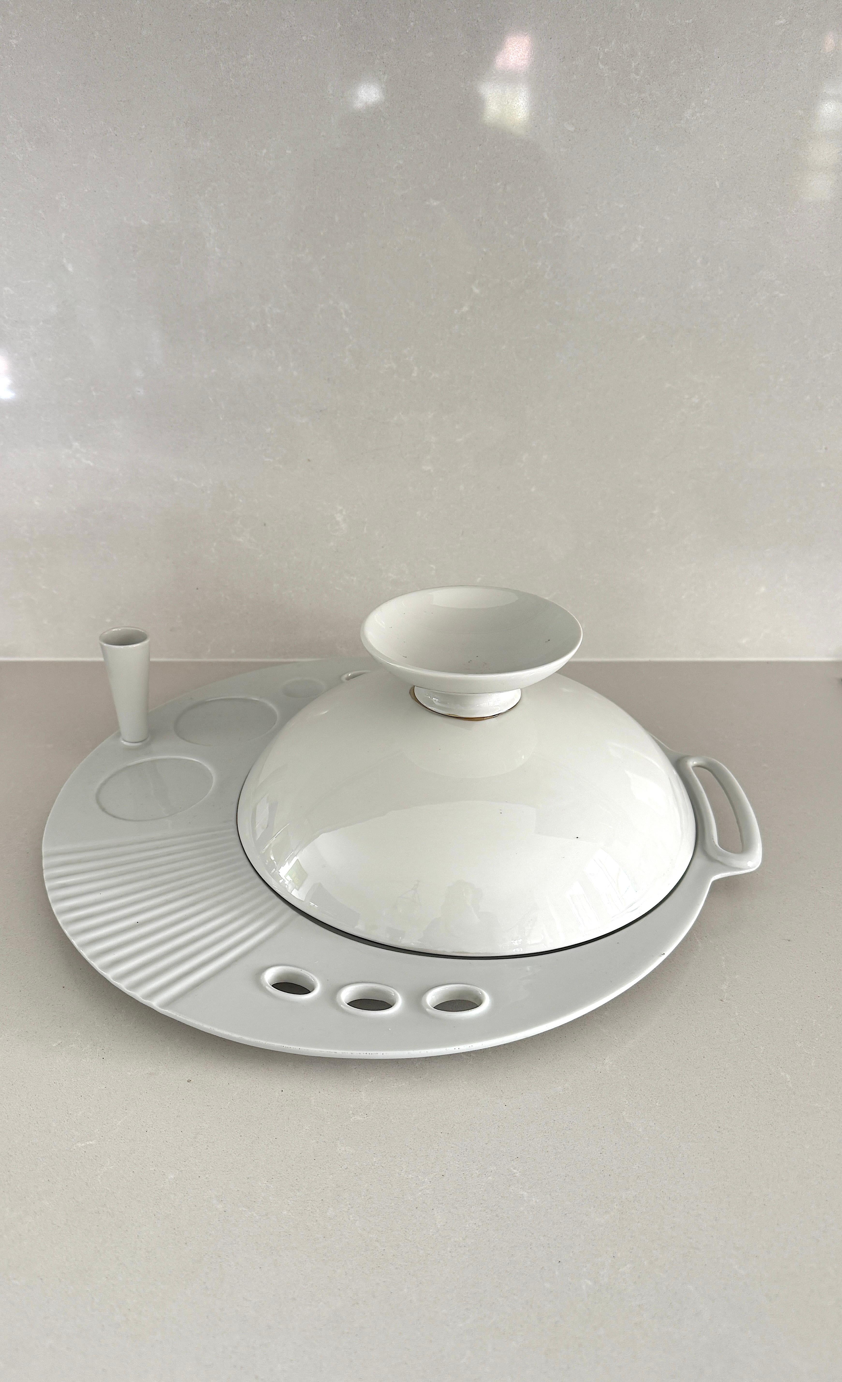 Raro juego personal mod. Oyster diseñado por Massimo Morozzi en 1987 y producido por Tendentse, Italia.
Juego de cerámica compuesto por un plato/bandeja con cubertero, portaflores, espacio para colocar un vaso y plato/tapa sopera.

Muy buen estado
