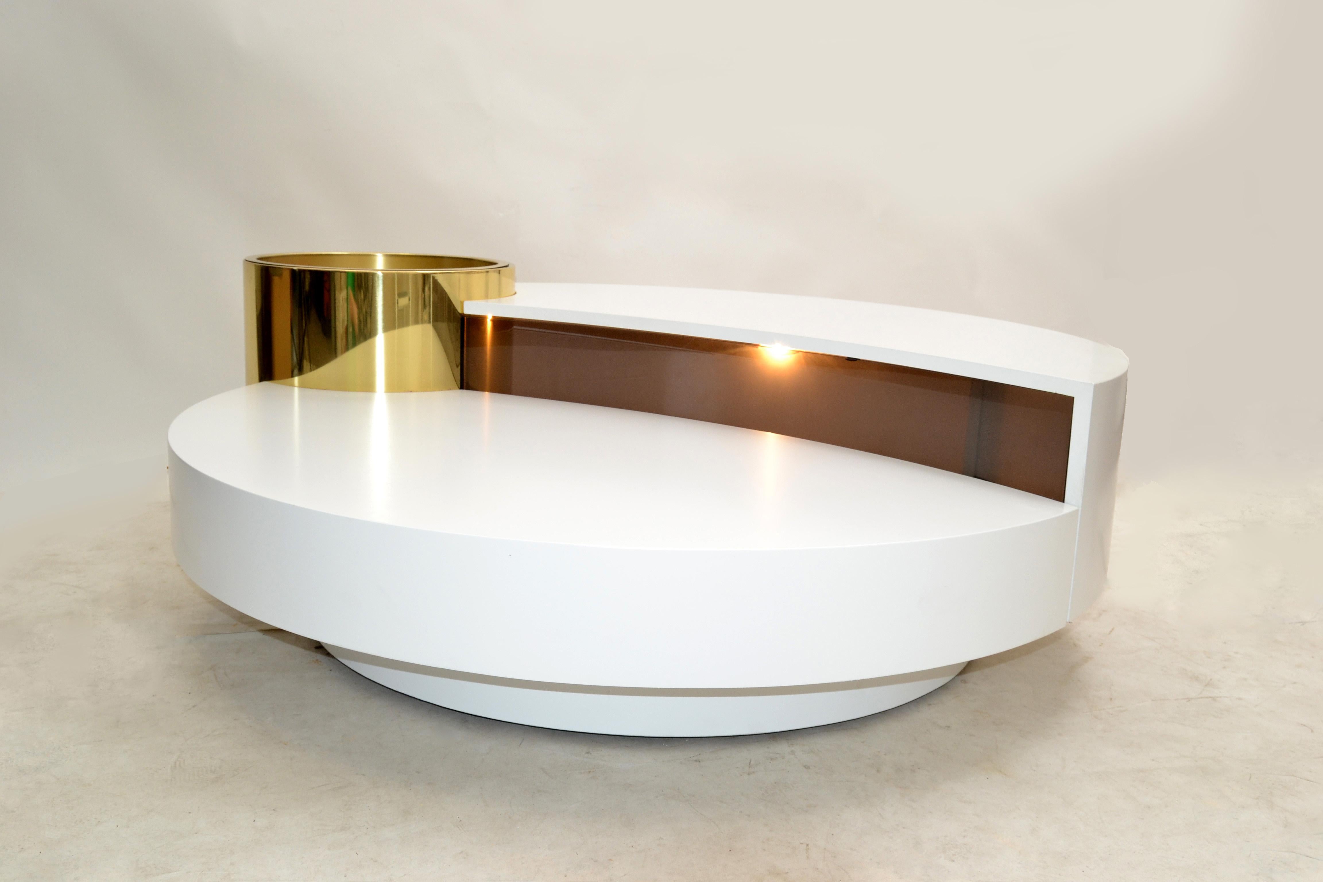Original Massimo Papiri rotating wood and brass coffee table with dry bar manufactured by Mario Sabot in Italy, circa 1970.
The interior is illuminated and exposed through a smoked Lucite shield.
The round brass compartment for the ice bucket or