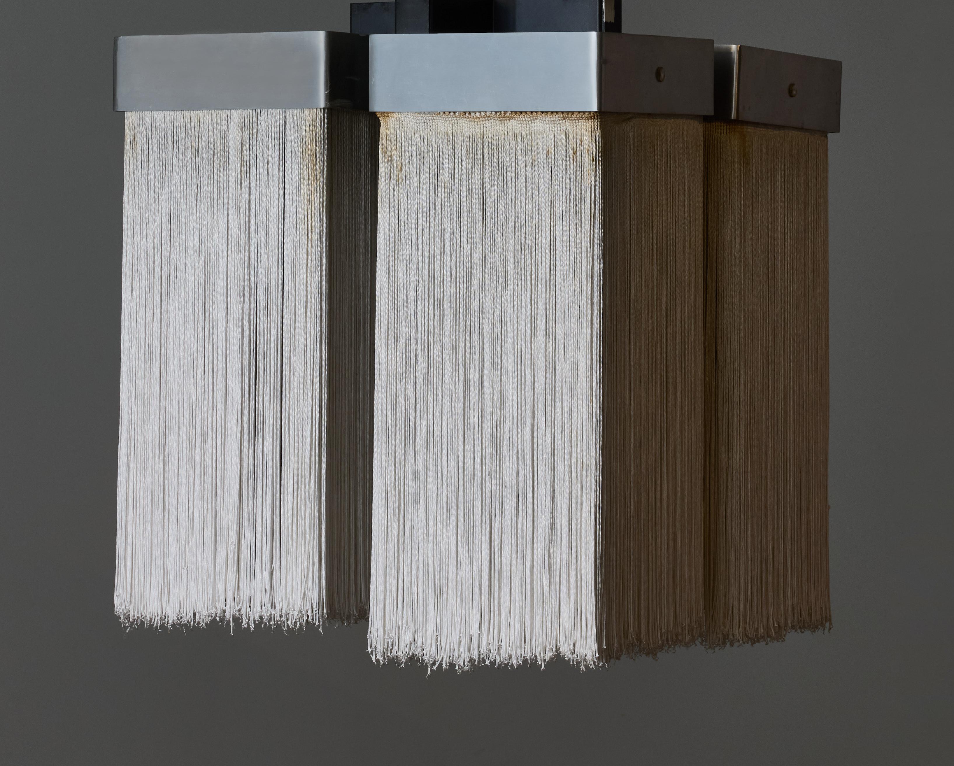 Ceiling light model 2049/4 designed by Massimo Vignanelli and made by Gino Sarfatti's Arteluce in 1964.

Made of four aluminium square frames from where hang fabric fringes surrounding the light sources.

Both frames are attached by black painted