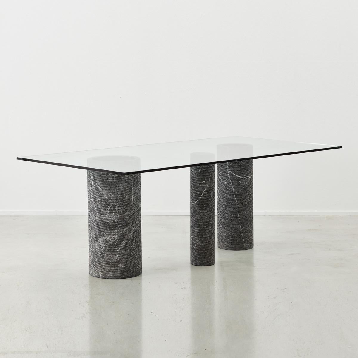 This striking dining table by Massimo Vignelli for Italian producer Casigliani is made from marble columns and glass. The three marble columns each vary in diameter, their facades systematically chipped to create a rough yet tactile surface texture.