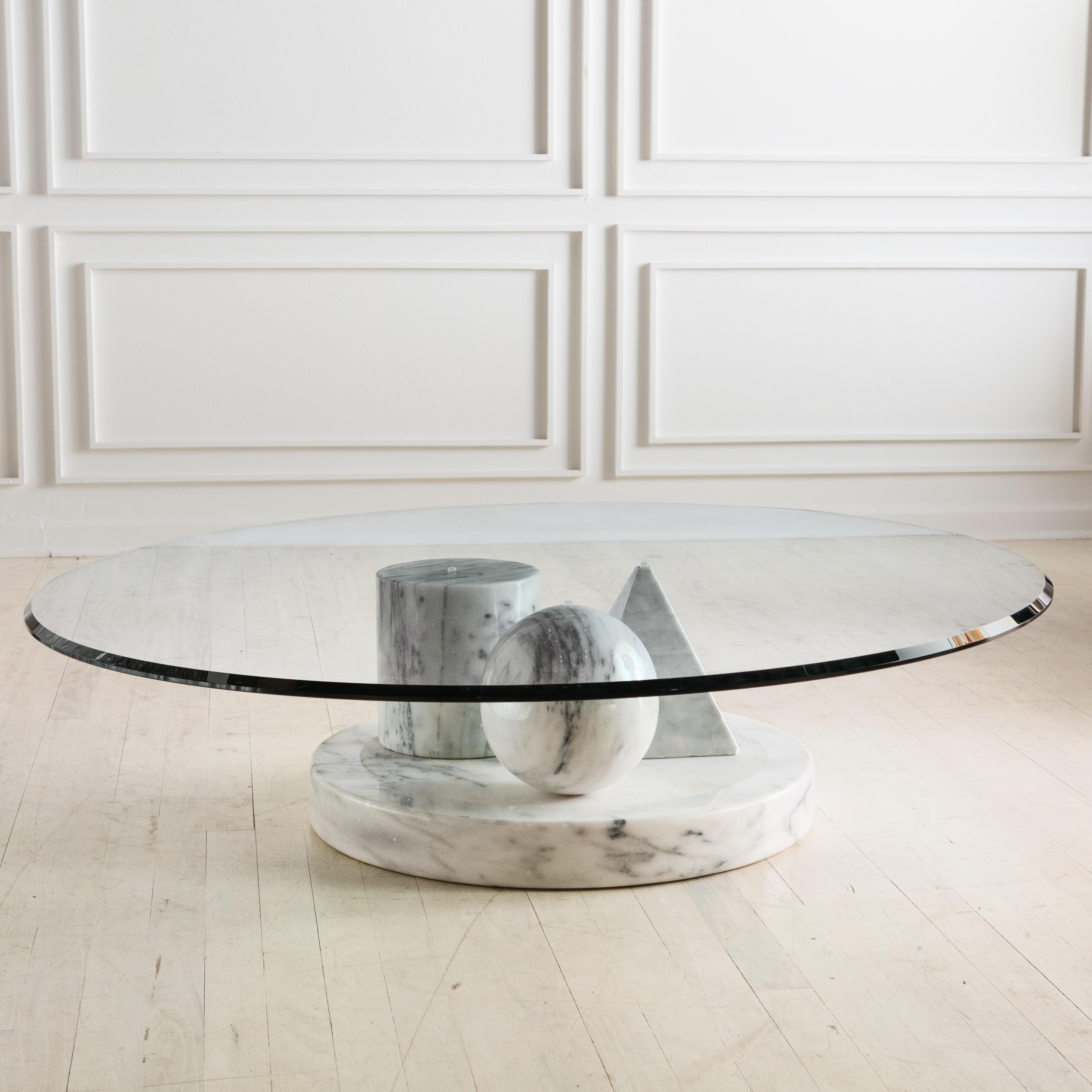 A dynamic use of marble and shapes, this Italian coffee table was designed by Massimo Vignelli for Casigliani. This features a marble triangle, sphere and cone all situated on a 23” thick and 23” diameter marble base on which a thick clear glass top