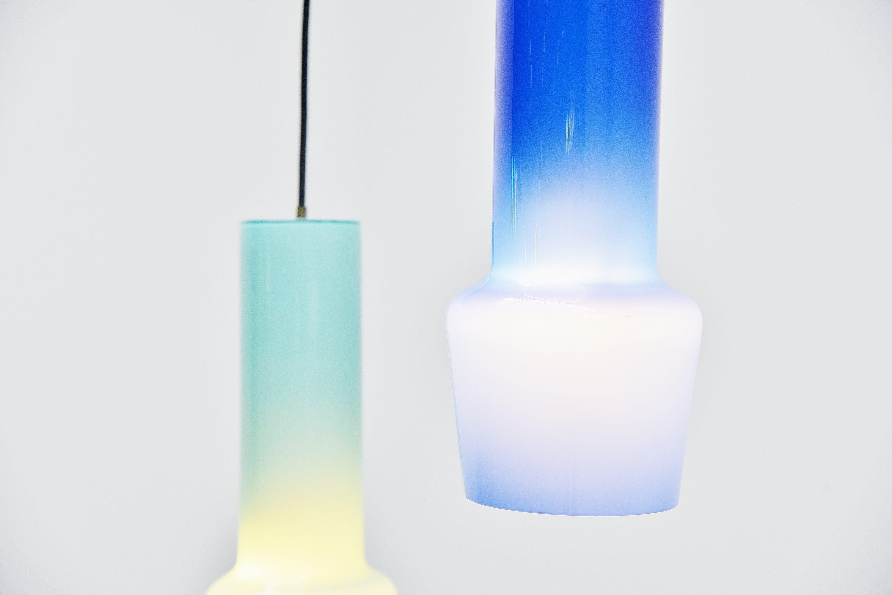 Fantastic pair of pendant lamps designed by Massimo Vignelli and manufactured by Venini, Italy, 1960. The lamps have a nice light and dark blue color. Because of the white inner glass they have a nice and deep color. The lamp have a brass fixture on