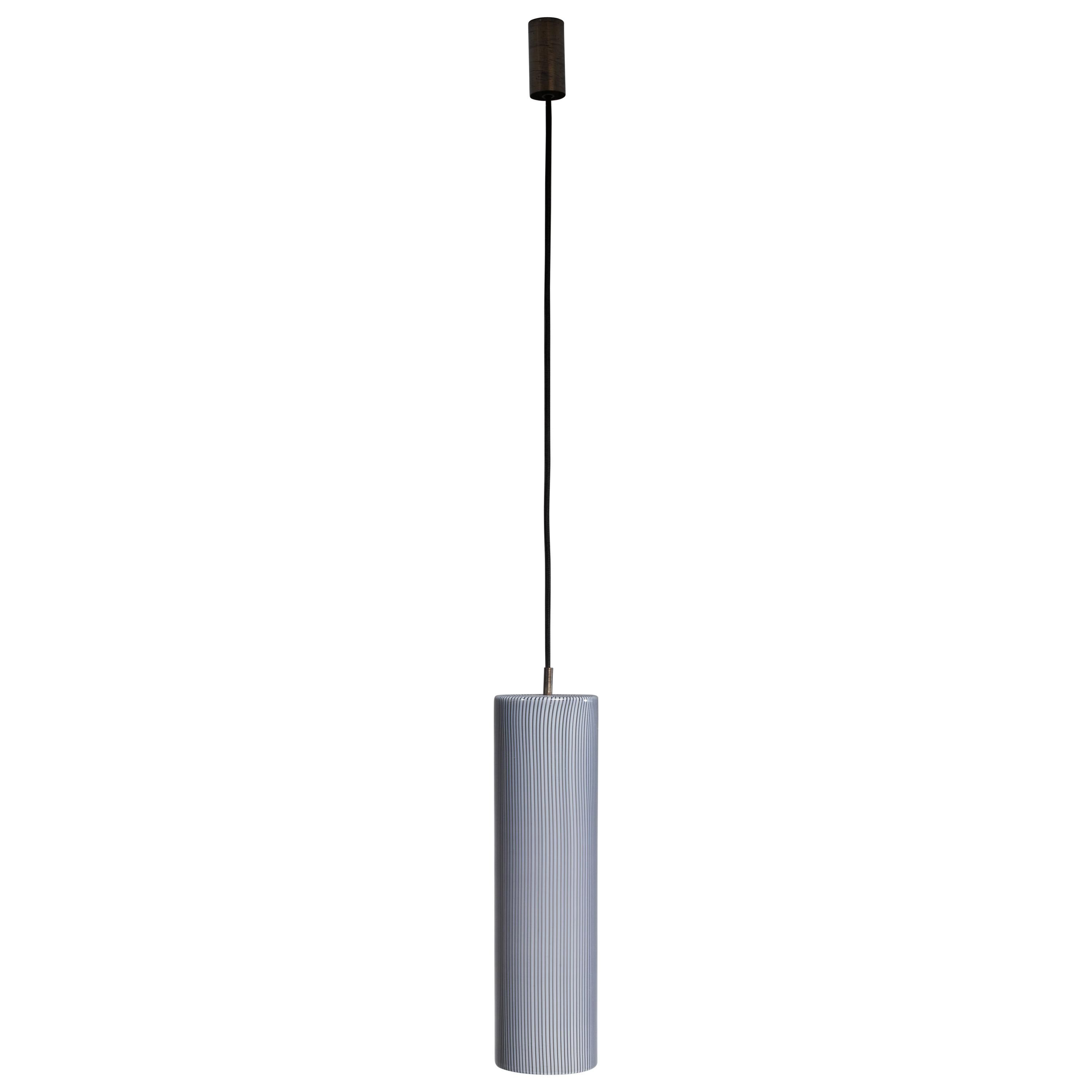 A large cylindrical glass pendant by Massimo Vignelli with thin black stripes by Vistosi, Italy. It is made with cased glass with a brass mounting. In excellent condition. The total drop can be adjusted to your requirements.