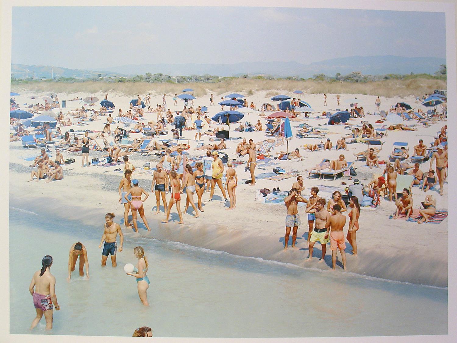 This diptych, part of the well-known Massimo Vitali Landscape with Figures portfolio, shows two views along the same beach, where the crowd wades in the water, chats, suns, strolls, and watches each other.  