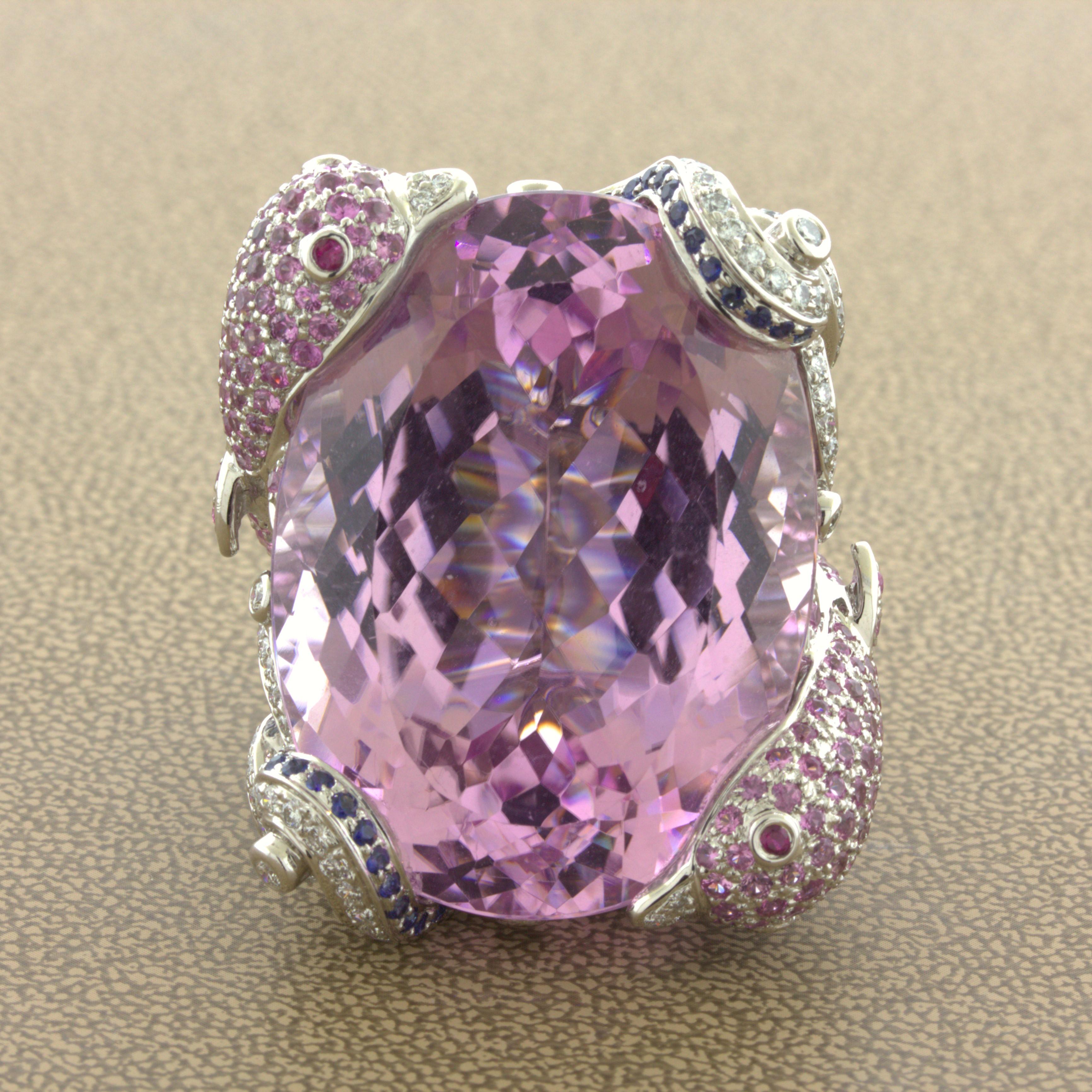 A super unique and out of this world cocktail ring! It features an amazing 1.07.08 carat bright barbie-pink kunzite surrounded by a detailed ocean and dolphin motif. There are two dolphins studded with 6.39 carats of round pink sapphires and ruby