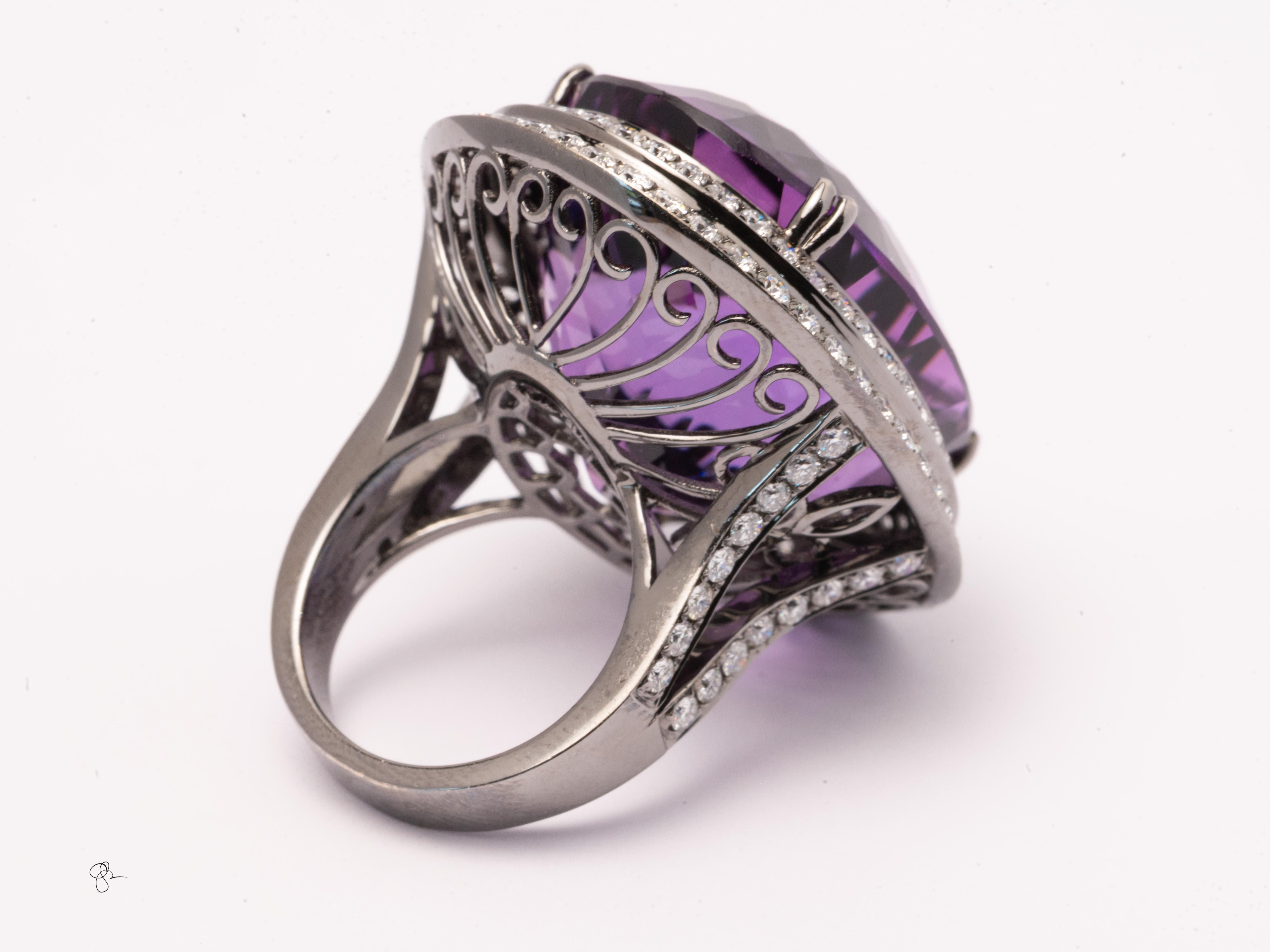 This extraordinary statement ring features a huge faceted fine oval shaped amethyst set in 30.1 grams of 18k white gold, surrounded by approximately 5.5 carats of sparkling clean white natural round diamonds in a double halo design. The bold,