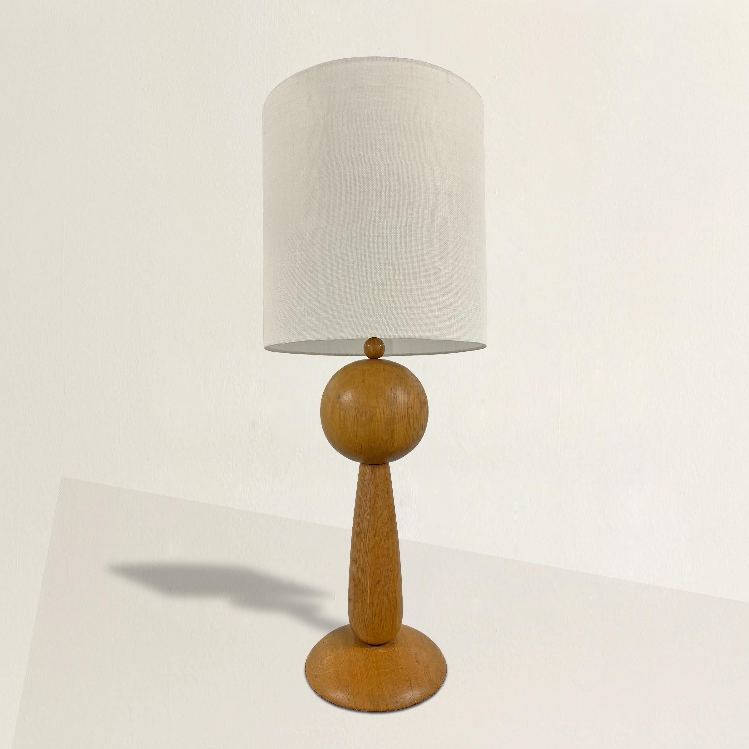 This 1950s French Modernist sculpture oak table lamp is a stunning exemplar of mid-century design, encapsulating the essence of the French Modernist movement. Crafted from massive oak, its form exudes both strength and elegance, a hallmark of this