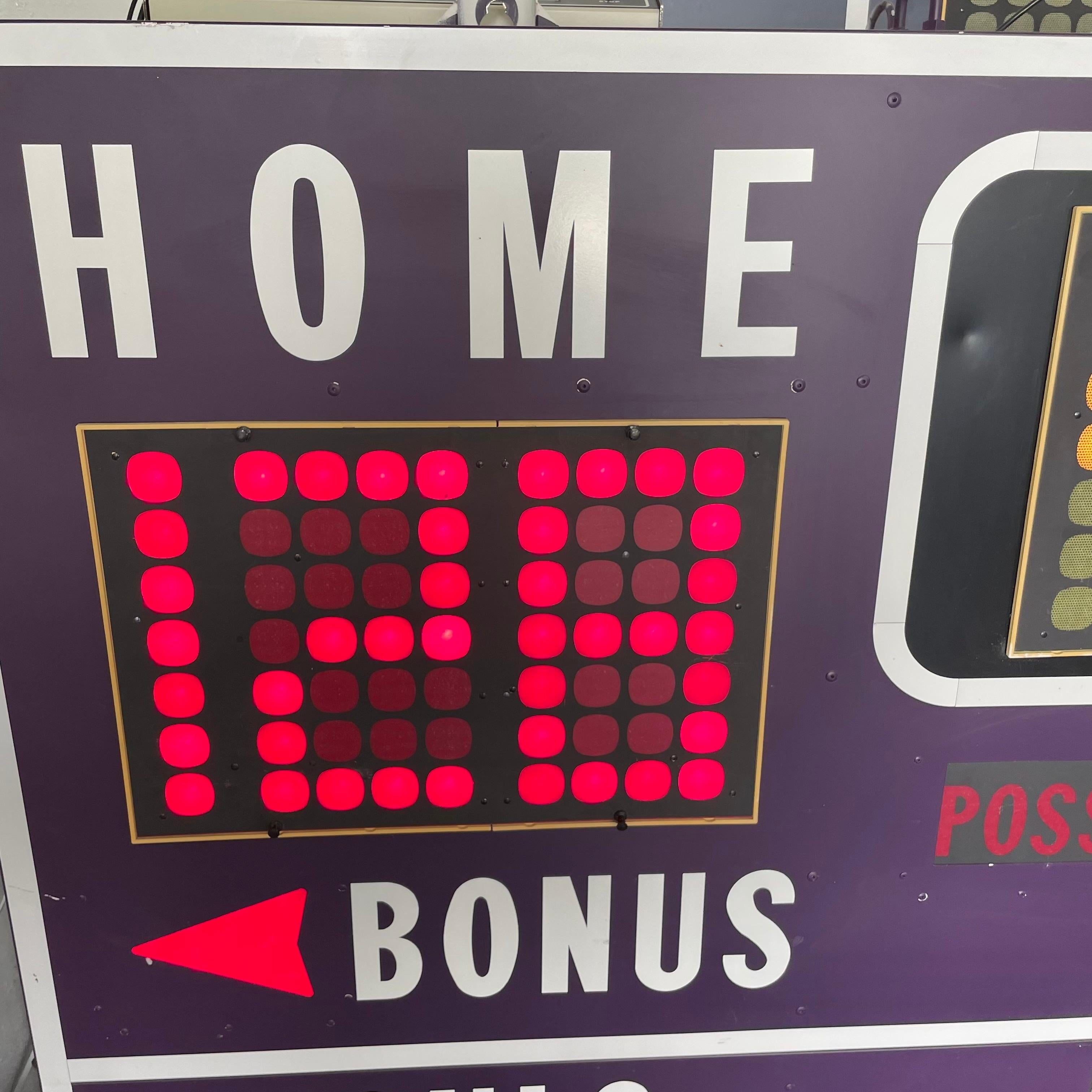 9 foot long basketball scoreboard by Fair Play. Made in the 1970s. Retired from a high school in Chicago. Dark purple frame. Comes with working controller. Scoreboard features a running clock, home and visitor score, period, bonus/possession, and