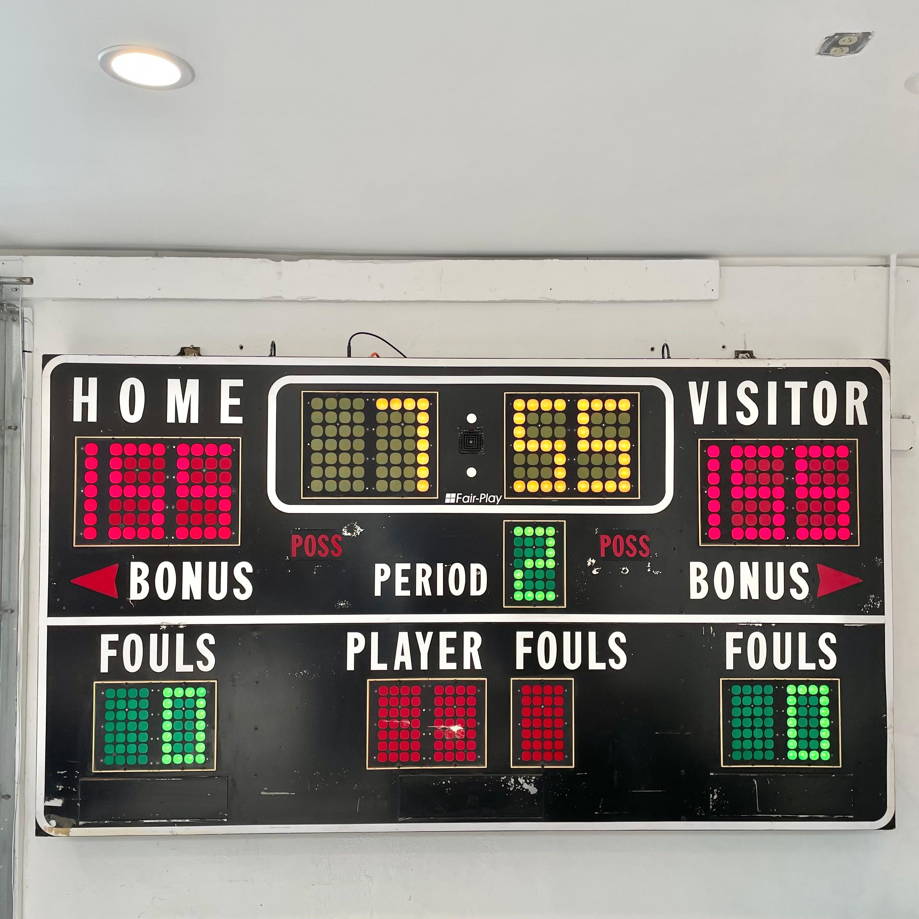9 foot long basketball scoreboard by Fair Play. Made in the 1970s. Faded black frame with nice patina. Comes with working controller. Scoreboard features a running clock, home and visitor score, period, bonus/possession, and player/fouls all