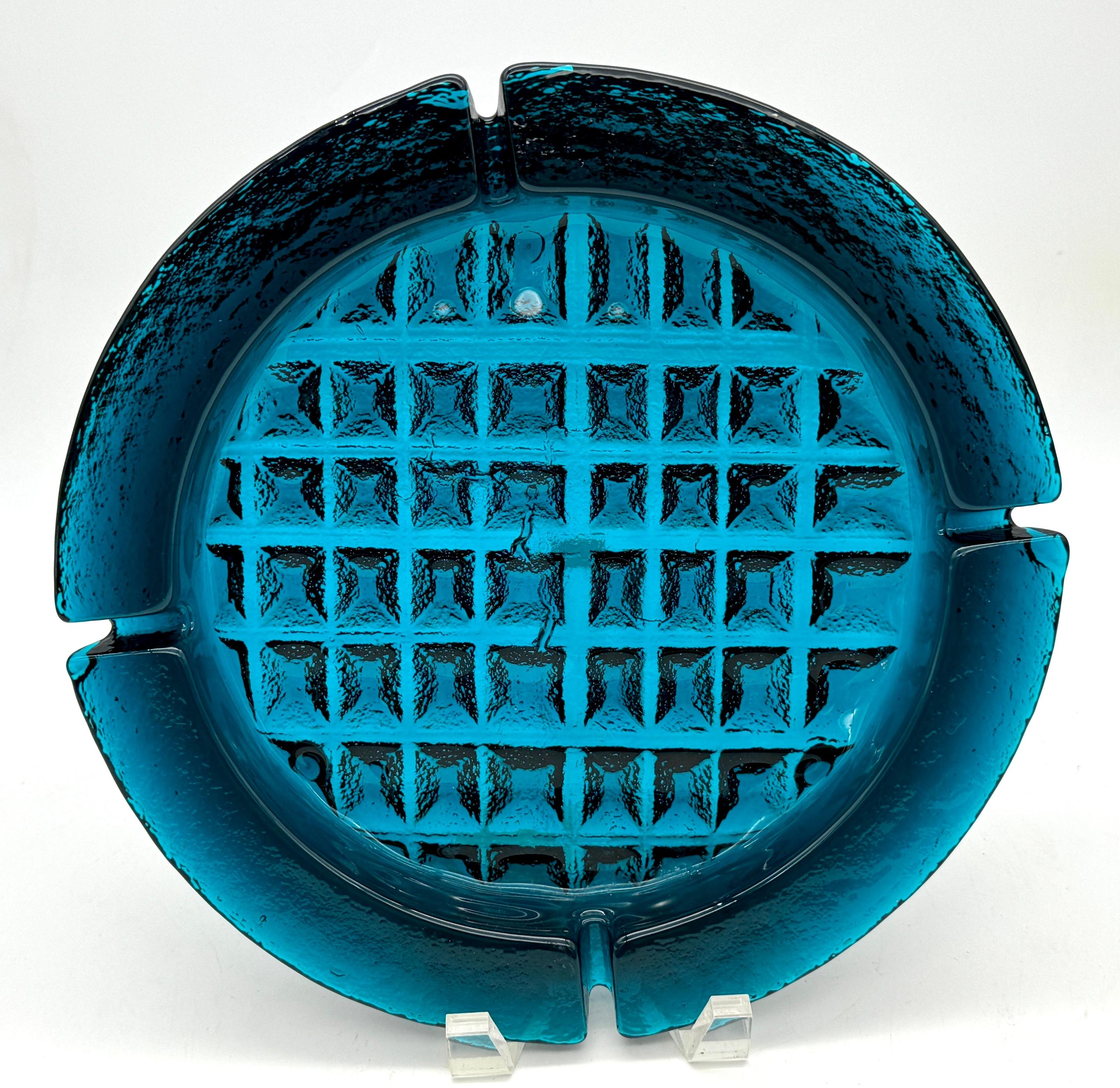 Massive 1970s Blenko 'Caribbean Blue' Brutalist Ashtray 
USA, circa 1970s

Transport yourself to the vibrant era of the 1970s with this striking piece of Blenko craftsmanship: a massive 1970s Blenko 'Caribbean Blue' Ashtray. This iconic ashtray