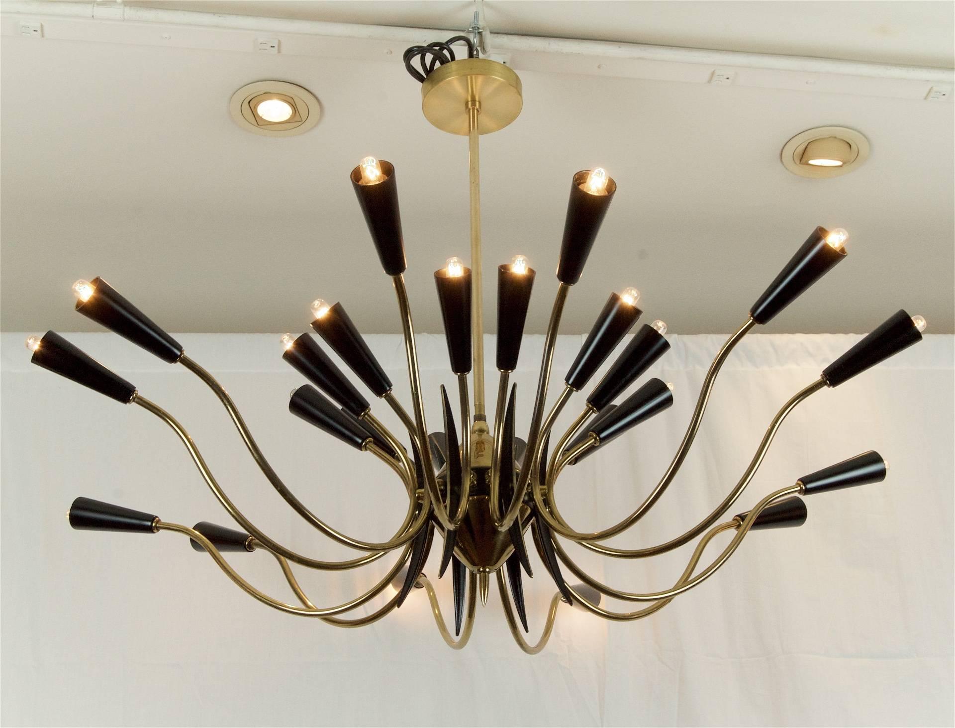Substantial and massive 1950s Italian chandelier in the style of Stilnovo, the 24 arms of upwards and downwards facing brass capped by black enameled Bakelite 41bulb cups; the central body in enamel and brass conical form with tined black and brass