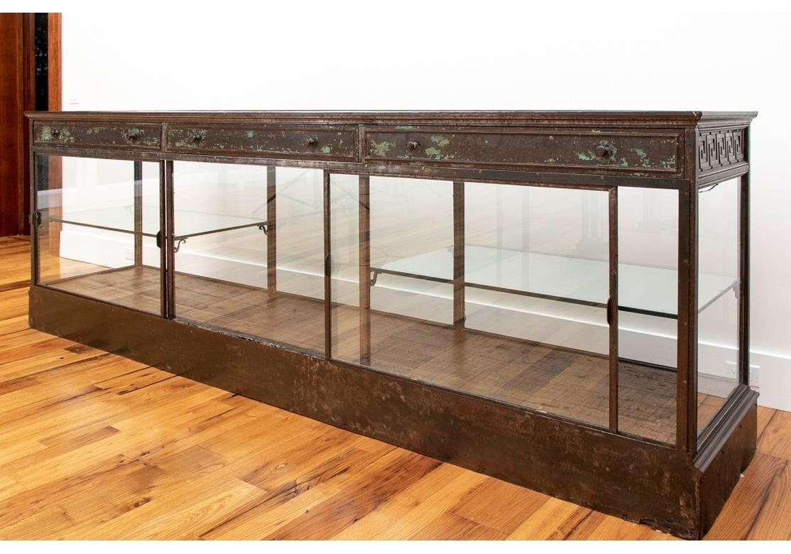 A massive and rare industrial era shop counter/ display cabinet with fine craftsmanship, great solidity and great detail. Constructed of wood with metal overlays. The oak top with inset brown leather surface. With a glass front, back, and sides, and
