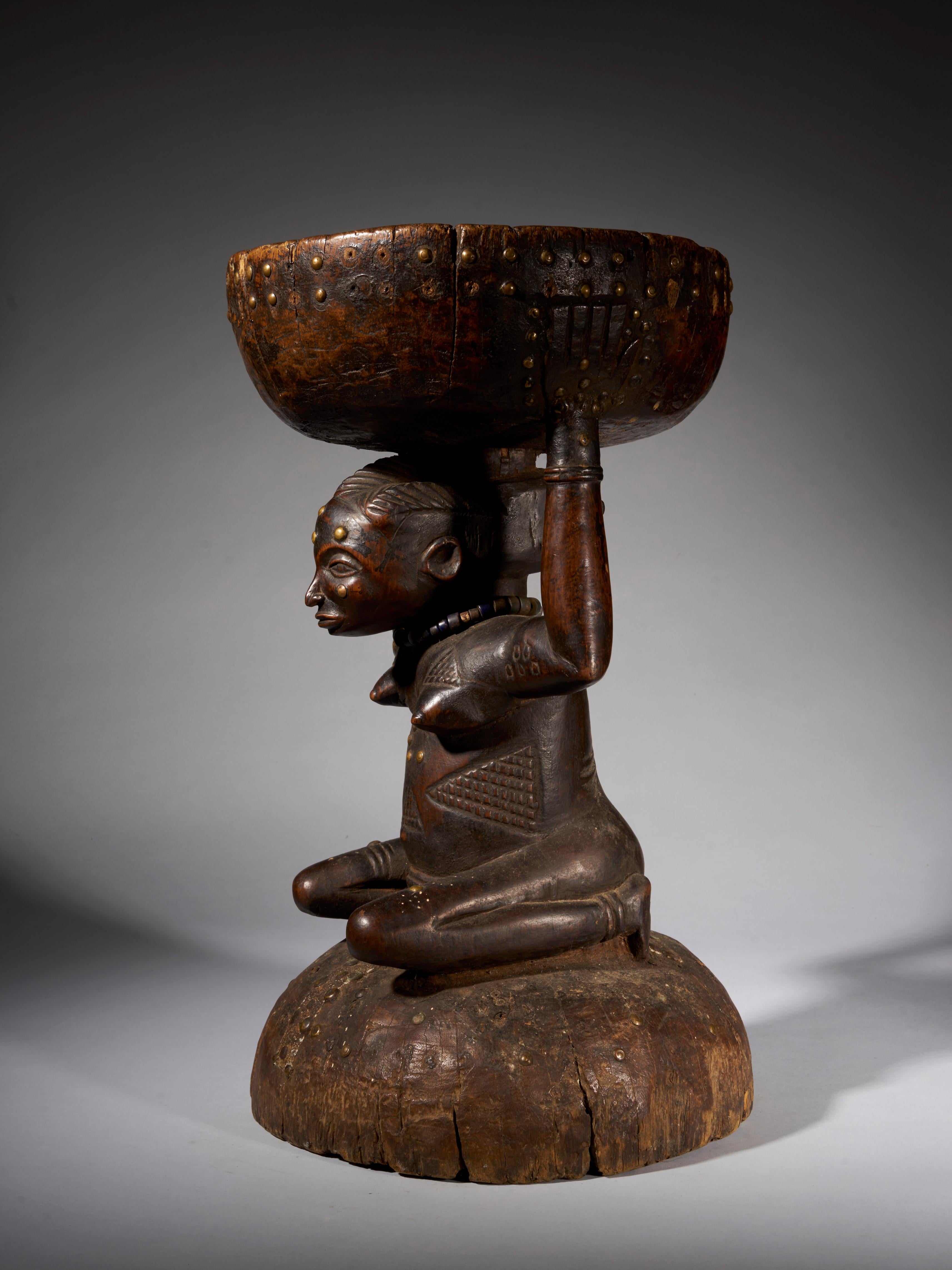 The stool represented here is a typical Caryatide stool of the Zela people in the Democratic Republic of Congo. The stool is carved out of wood and is held up by a kneeling woman covered with typical Zela scarifications,showing her high ranking