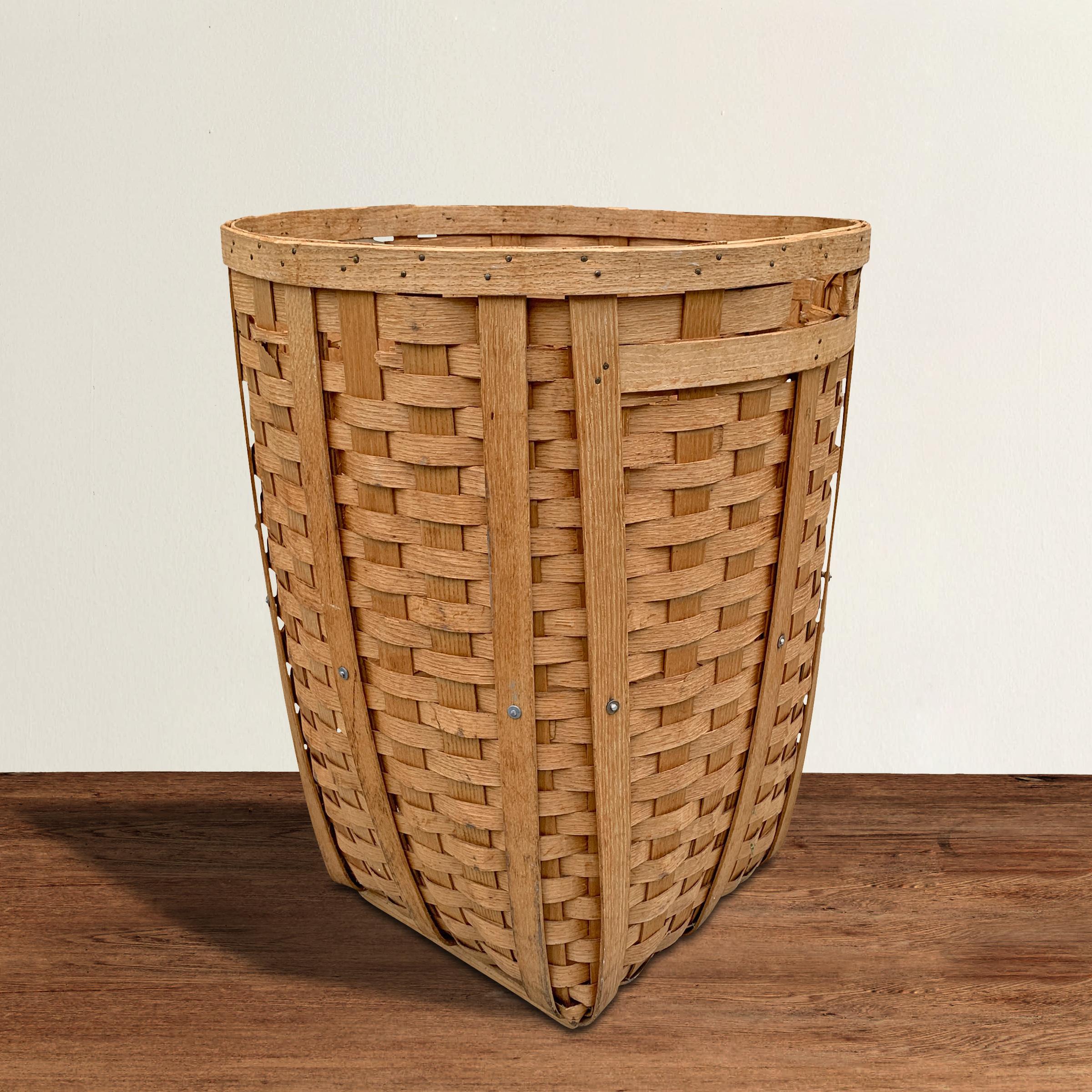 A fantastic massive and tall American woven oak splint basket with a handle on each side, and wooden supports along the bottom. Perfect for storing pillows, blankets, toys, or if you're that person, your dog’s toys.