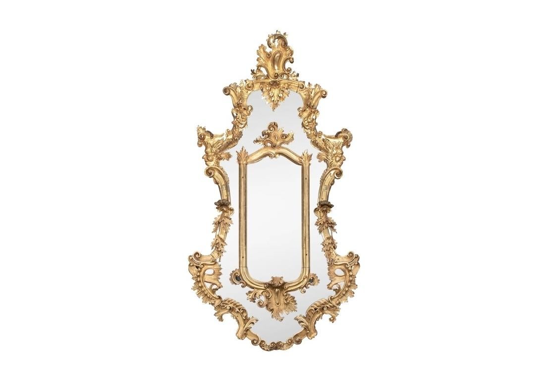 Provenance : Sotheby's, NY (1/89). Une forme de cartouche allongée avec des détails élaborés de volutes feuillues et une crête en forme de cartouche. Les deuxièmes projections avec des masques sur les longs côtés incurvés. Le miroir est composé de