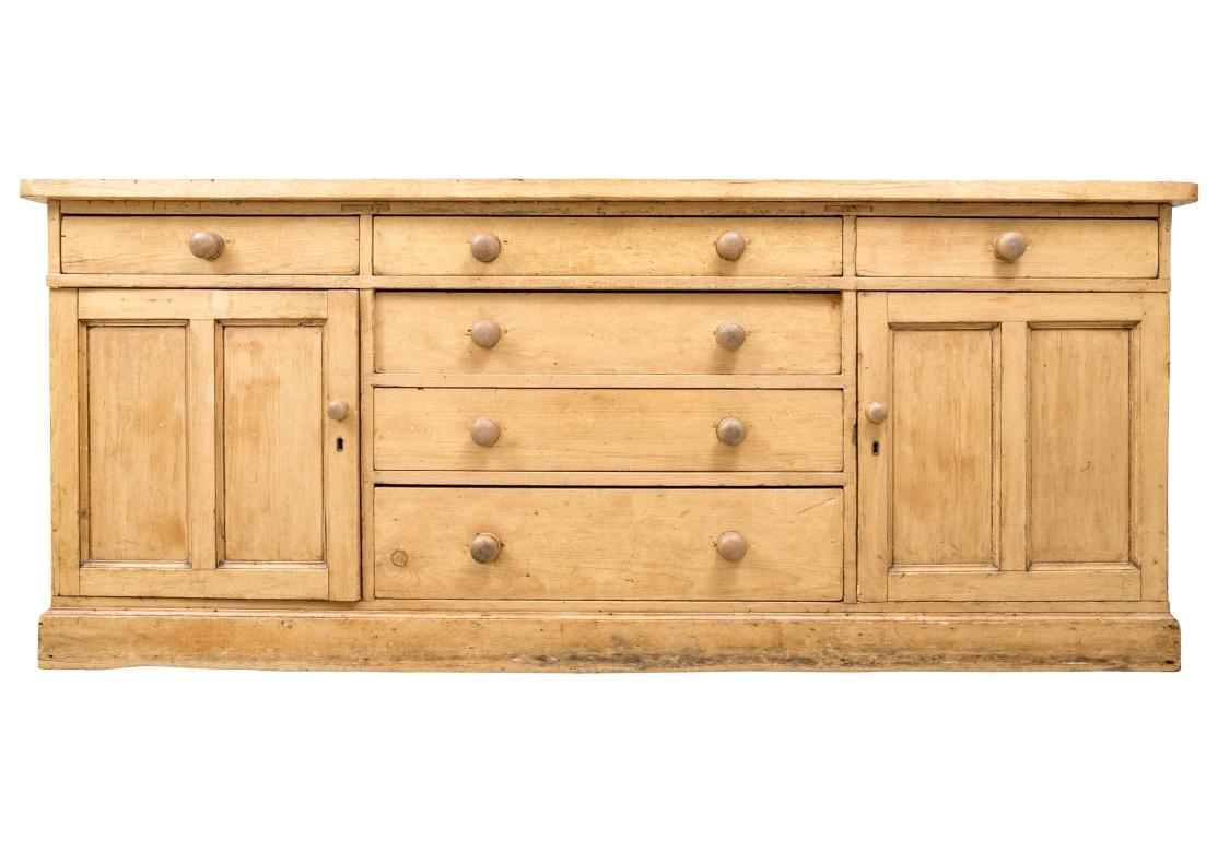 A particularly desirable massive and long Antique Pine Cabinet with a soft hand and lots of storage for a multitude of applications; kitchen, living room, hallway, etc. The solid pine cabinet has a thick top with rounded front corners above four
