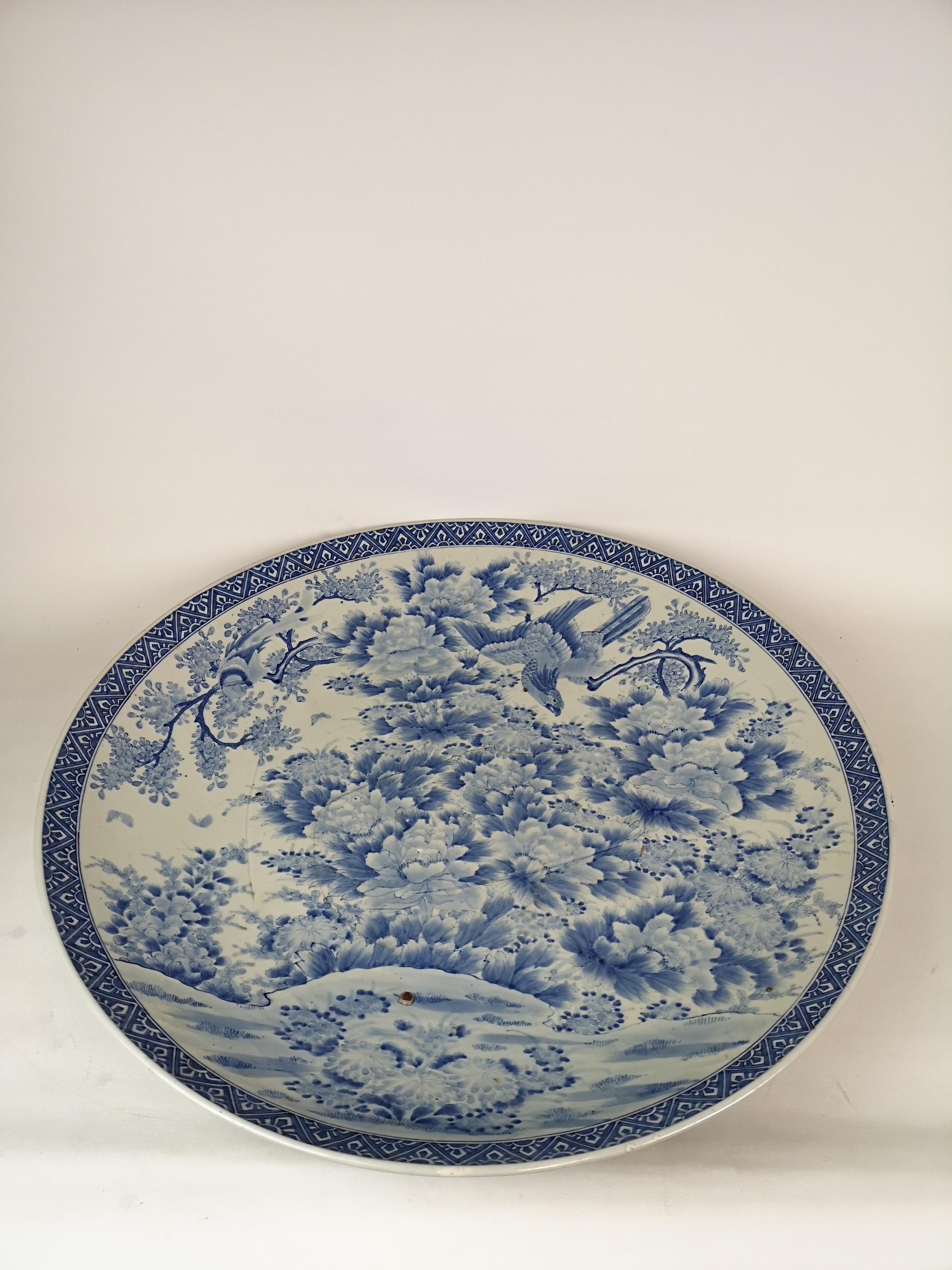 This very large plate made in Japan during the Emperor Meiji time 1868-1912. Wonderful blue pattern on fine porcelain.
There is a crack that’s shown throughout the middle, but the plate gives a beautiful sound as a nice porcelain does. 

Good fair