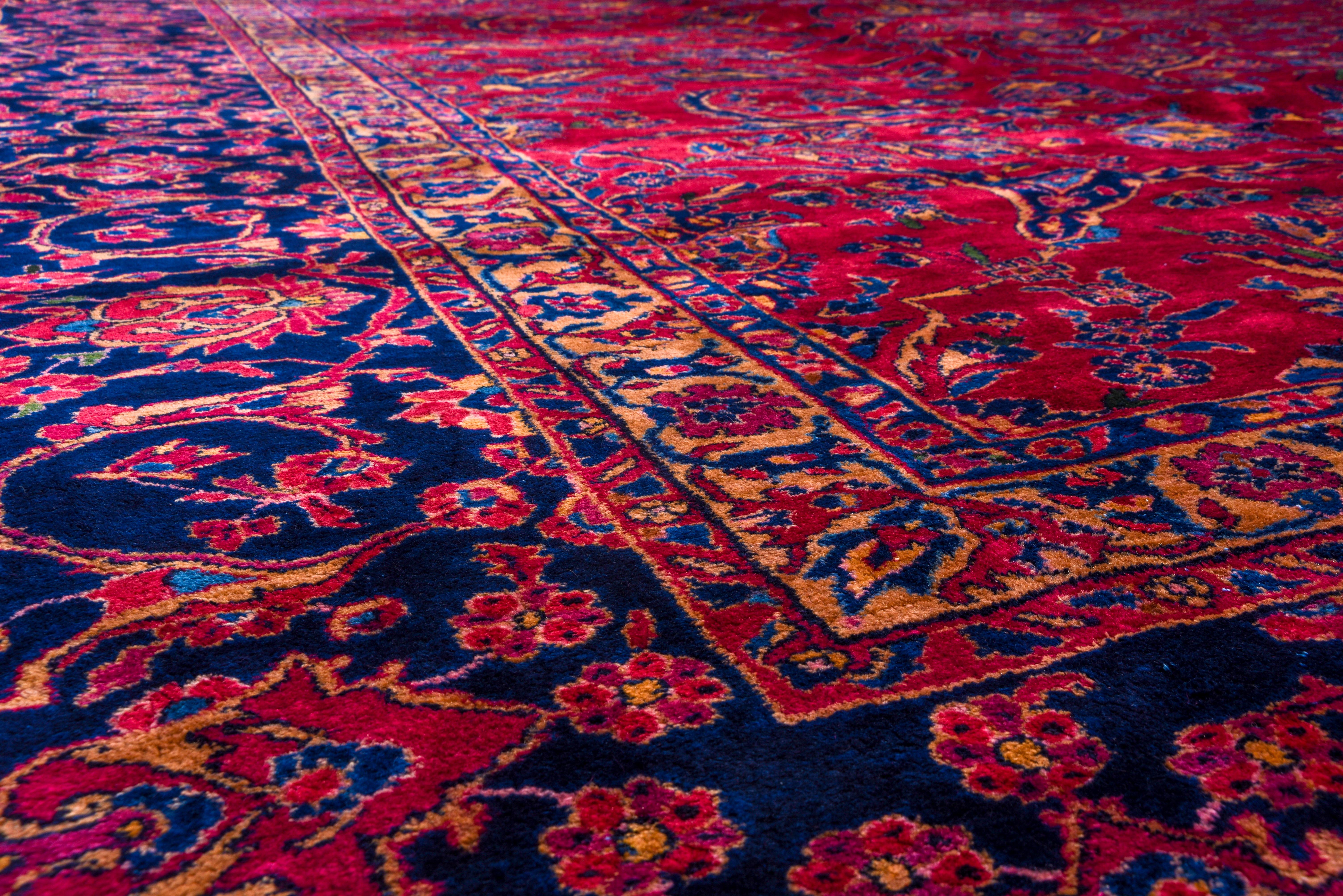 Of better Mohajeran quality, thus enormous, medium weave, cotton foundation, good condition West Persian carpet presents a Classic red field with floral sprays swirling around an open centerpiece of navy forked arabesques and radiating petal