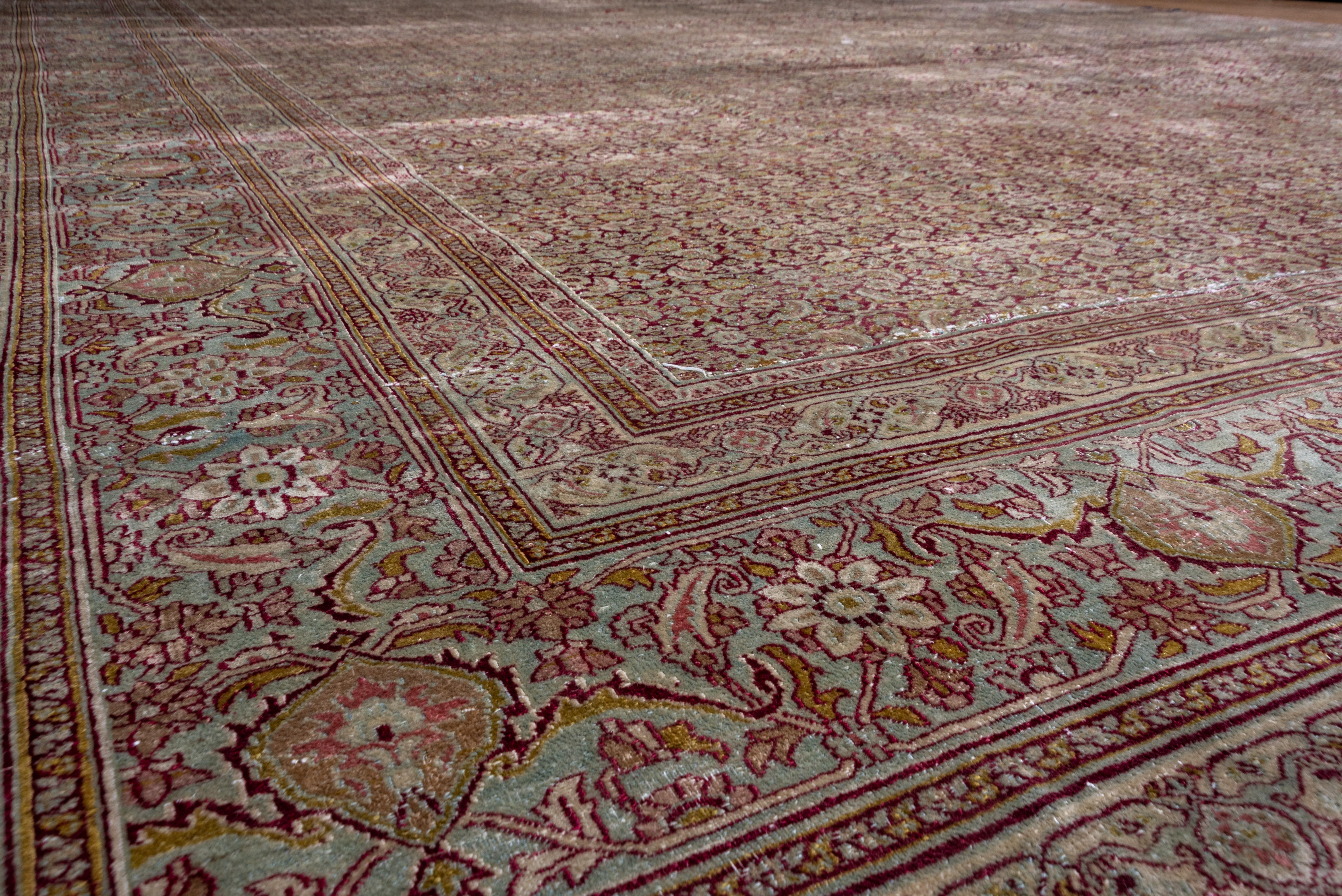 This NE Persian large city carpet displays a close allover Herati design on a dark and shiny wine red field. A virtually infinite Herati river. Abrashed powder abrashed with reversing barbed turtle palmettes, boteh leaves and octofoil rosettes.