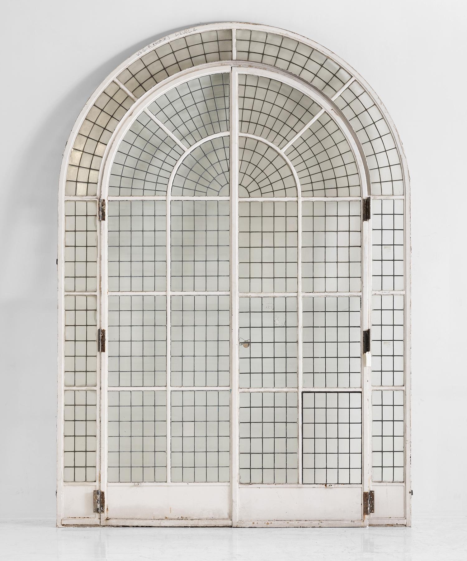 Massive arched doorway, England circa 1900.

Painted metal framed glazed doors. The glass is fixed with a mixture of copper and lead.