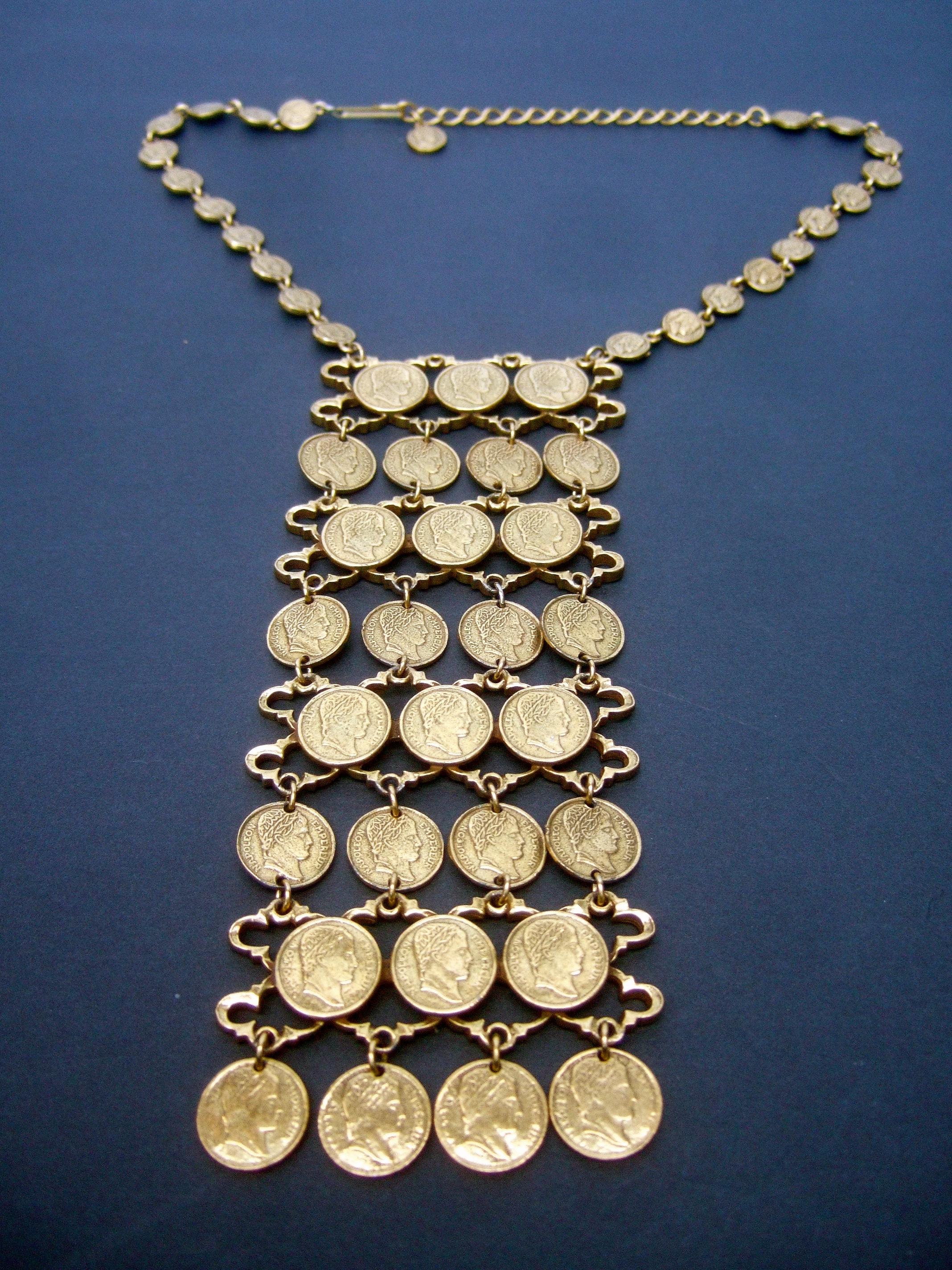 Massive articulated gilt metal coin bib necklace c 1970s
The unique necklace is designed with a collection 
of small scale Roman style replica coins 

The rectangular pendant is suspended from a chain 
comprised of smaller size coins. The four