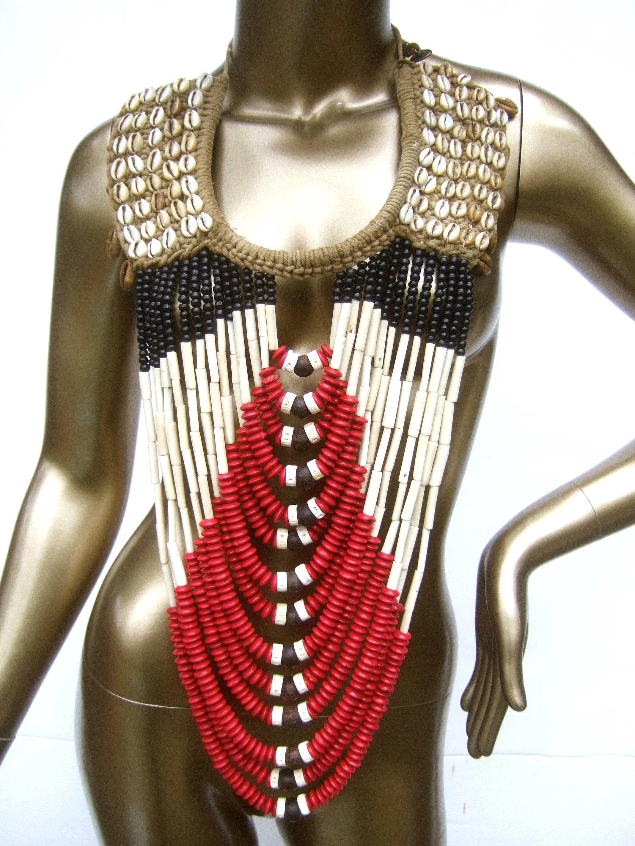Massive artisan ethnic tribal beaded statement necklace c 1980s
The huge scale handmade artisan necklace is comprised of
fourteen strands of graduated wood beads in red and black enamel  
Juxtaposed with elongated cylinder shaped beads in antler