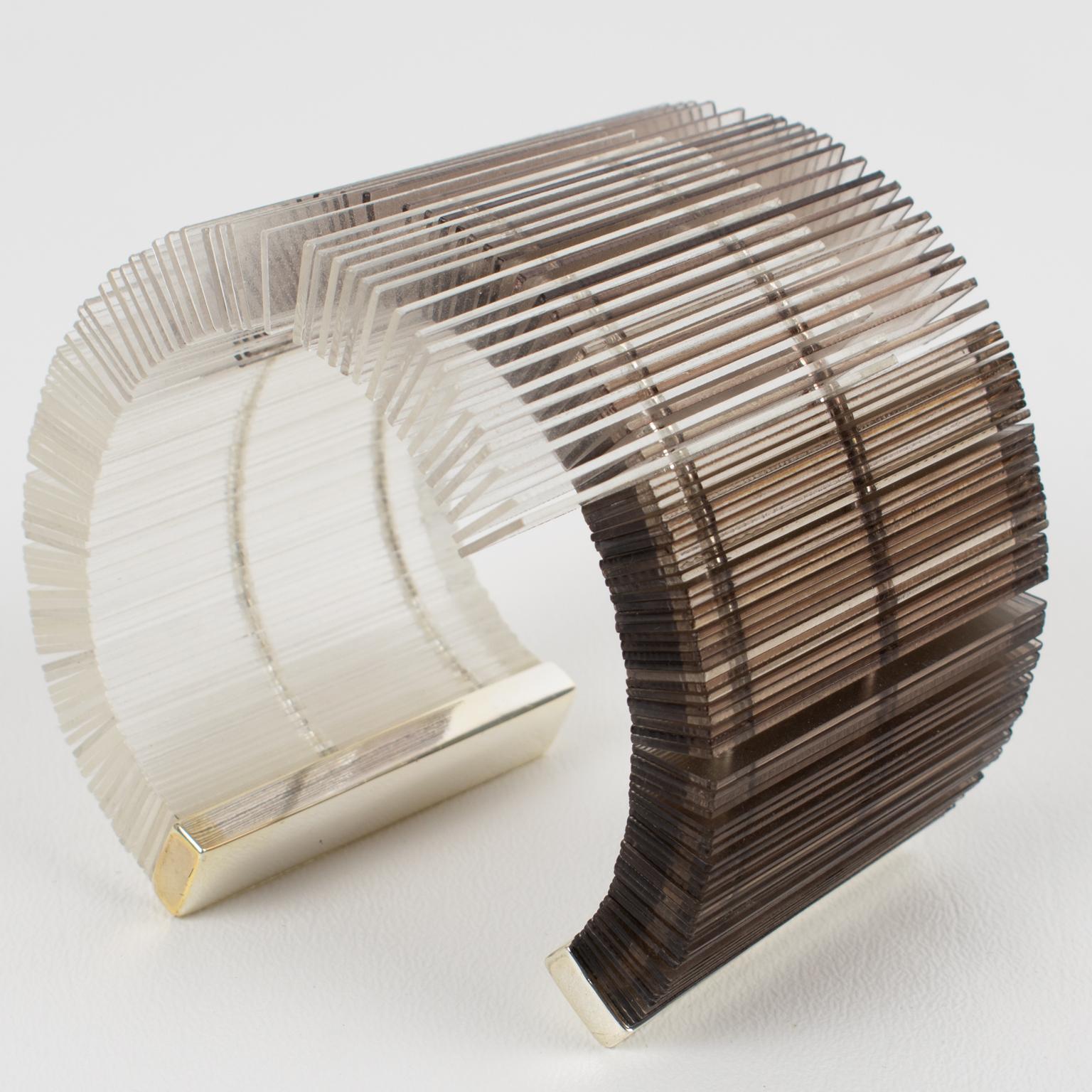 This stunning sculptural cuff bracelet bangle from the 1980s features an important asymmetric shape with geometric flat elements in clear and smoked gray Plexiglass or Lucite. The rare cuff bracelet ends with silvered metal tips. There is no visible