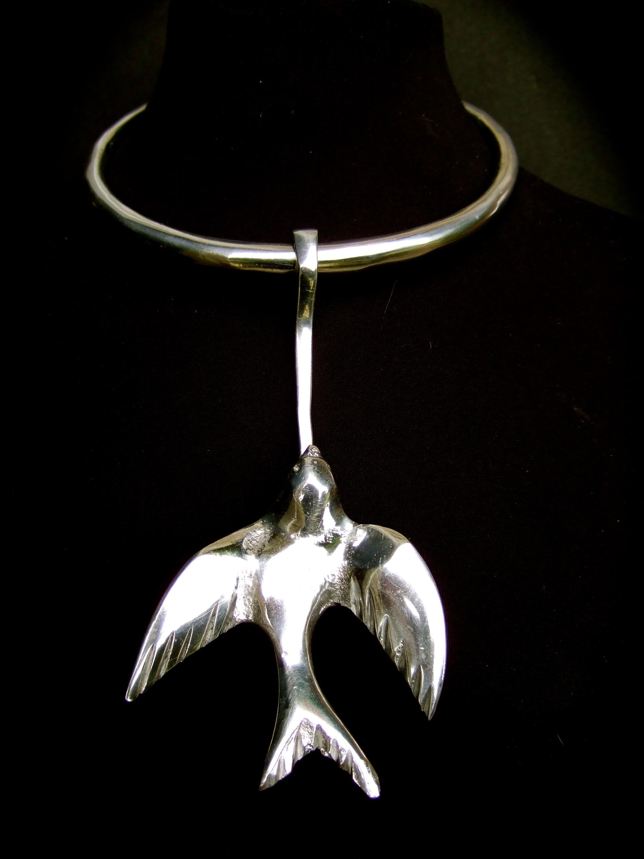 Massiccia collana girocollo articolata in metallo argentato d'avanguardia con disegno di uccello, anni '70 circa 
L'esclusivo girocollo artigianale è realizzato con una fascia rigida in metallo placcato argento.
Adornato con una grande figura di