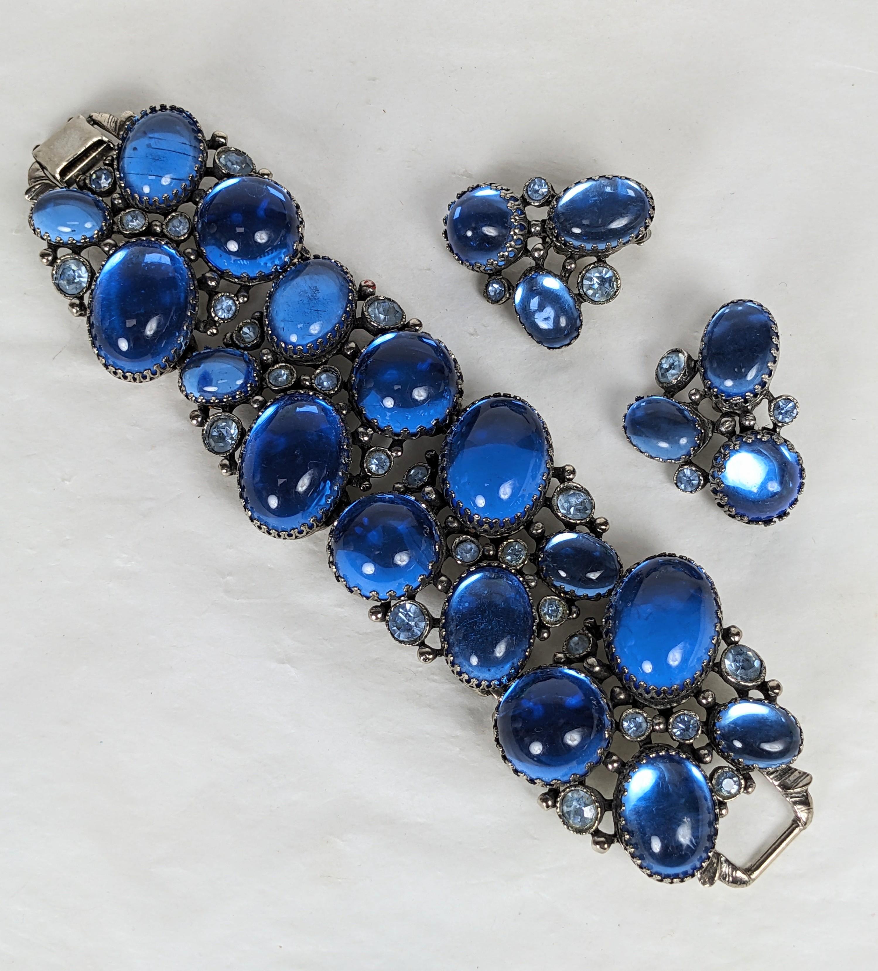 Llamativo conjunto de joyas de cabujones azules con brazalete macizo y pendientes de los años 50. Los grandes cabujones laminados de estilo Schiaparelli se mezclan con cristales facetados. Increíble escala, 7,5
