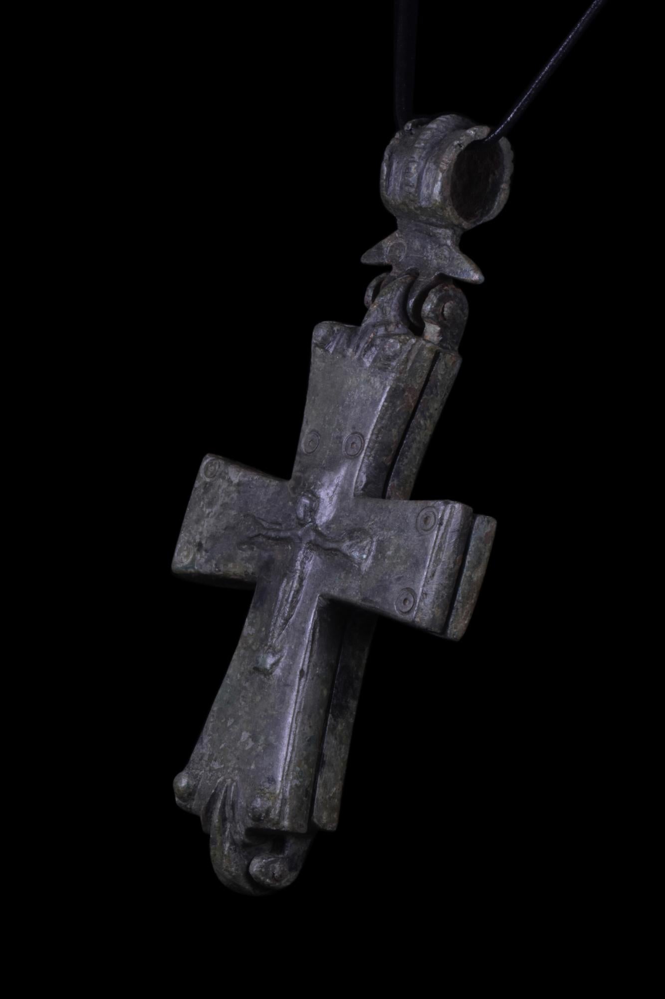 Ein byzantinischer Reliquienkreuzanhänger aus Bronzeguss mit zwei kreuzförmigen Platten, die sich zur Aufbewahrung von Reliquien oder Dokumenten öffnen lassen und auf beiden Seiten den gekreuzigten Christus darstellen. Reliquien, die physischen