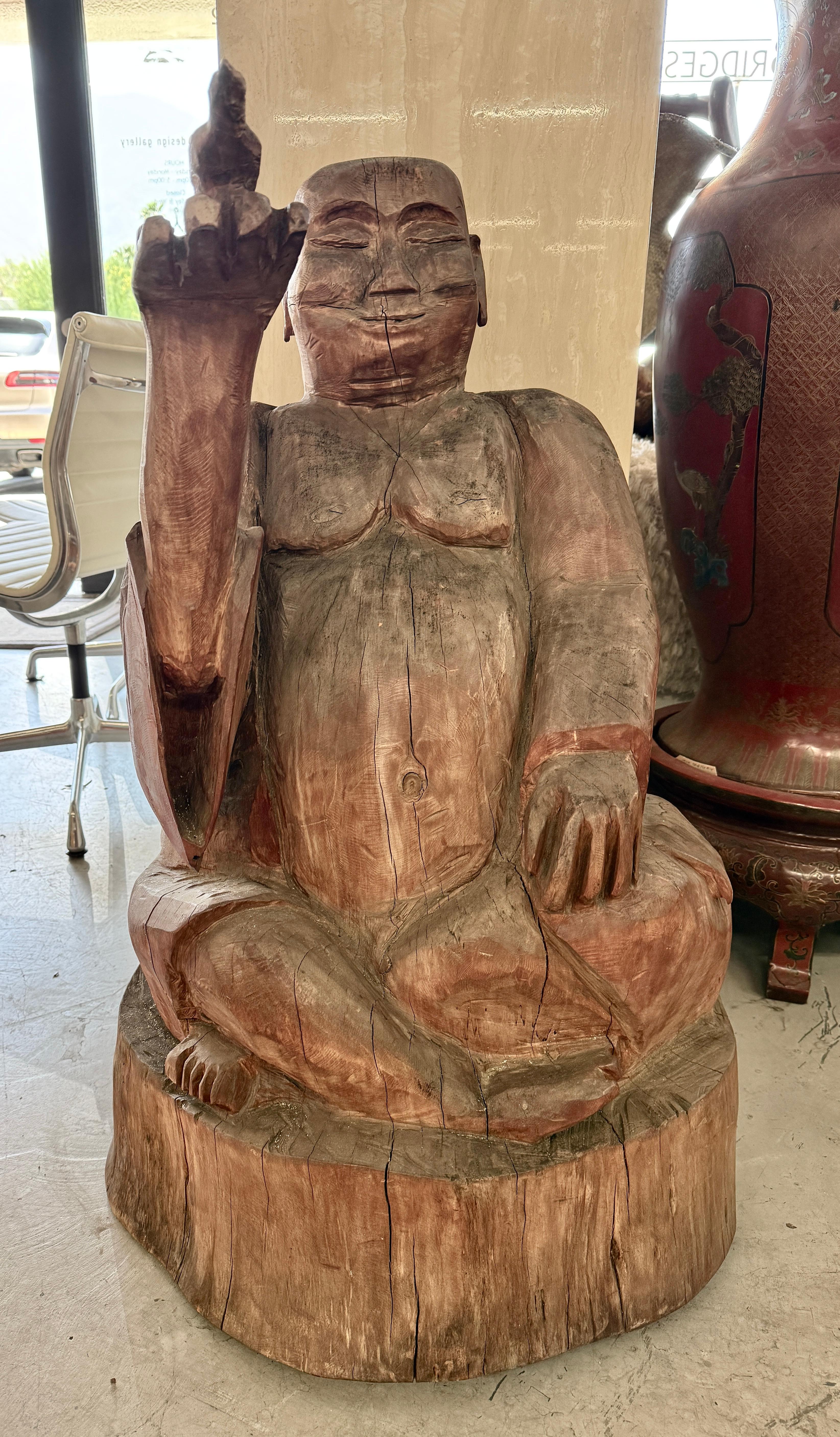 Eine wunderschöne holzgeschnitzte Buddha-Skulptur, die aus einem massiven Stamm geschnitzt wurde. Ich bin mir nicht sicher, aus welchem Holz es besteht, aber es ist extrem schwer. Der Buddha hält einen Vogel. Die Skulptur ist etwa 37 Zentimeter