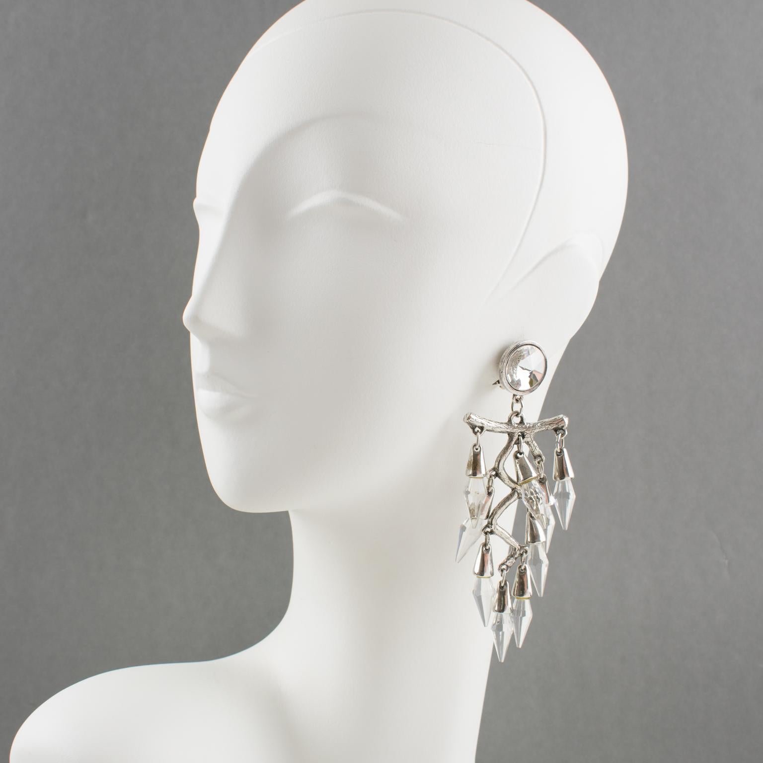 These lovely oversized chandelier clip-on earrings boast a romantic design with a dangle shape and a large silver plate metal carved stylized branch framing complimented with crystal faceted drop beads. There is no visible maker's