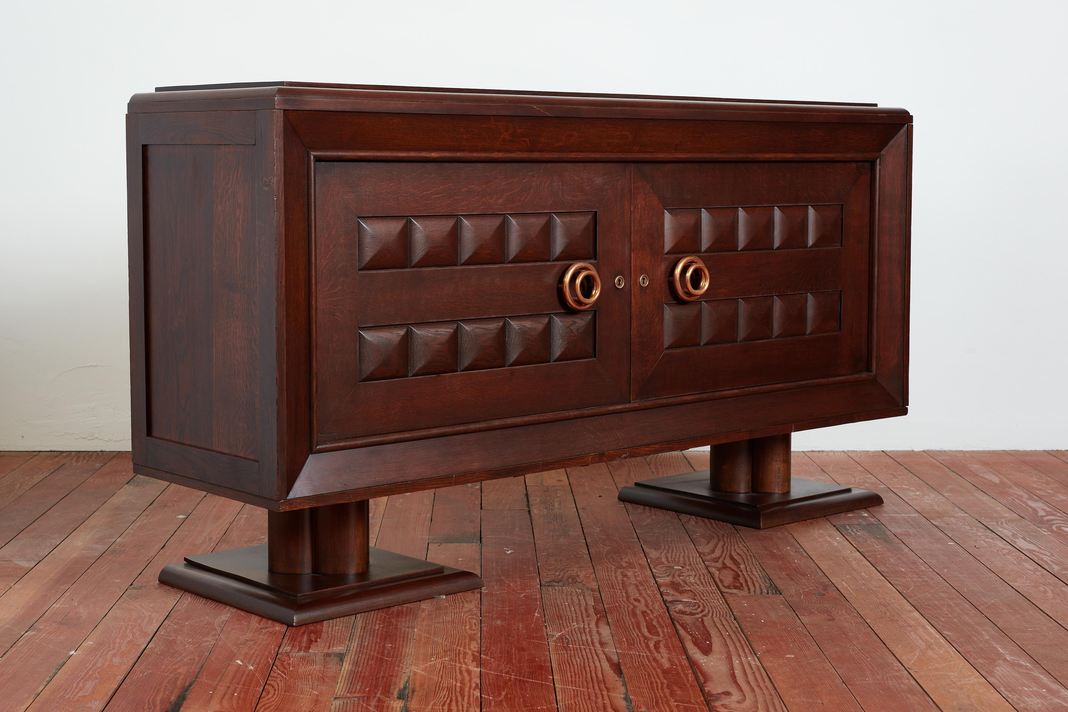 Large scale 1940s French sideboard cabinet designed by Charles Dudouyt with thick brass concentric circle handles. 
France, 1940s

Beautiful dark finish with 2 door panels with carved design.  Doors open revealing interior shelves with inlay and