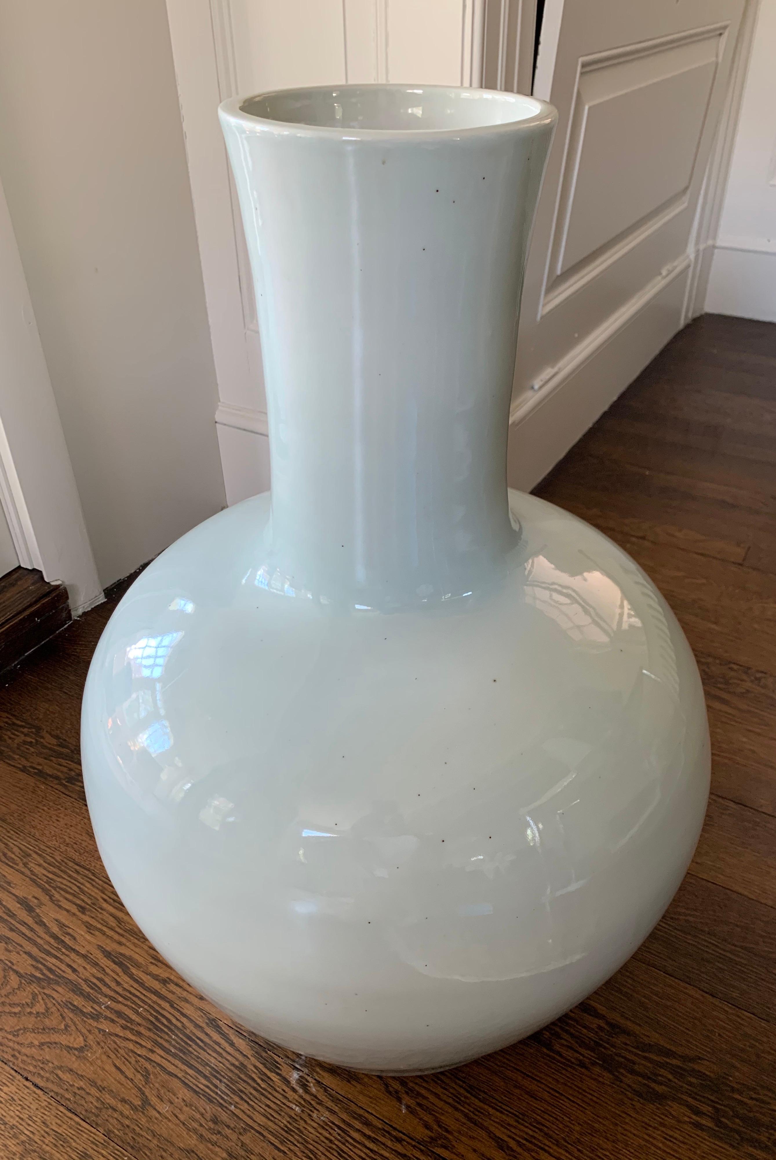 This extra large Chinese celadon vase is made of white porcelain covered overall with a soft green glaze of even tone. The body is symmetrical, elegant, and simple. It’s stark simplicity and beauty will stand alongside a collection in a traditional