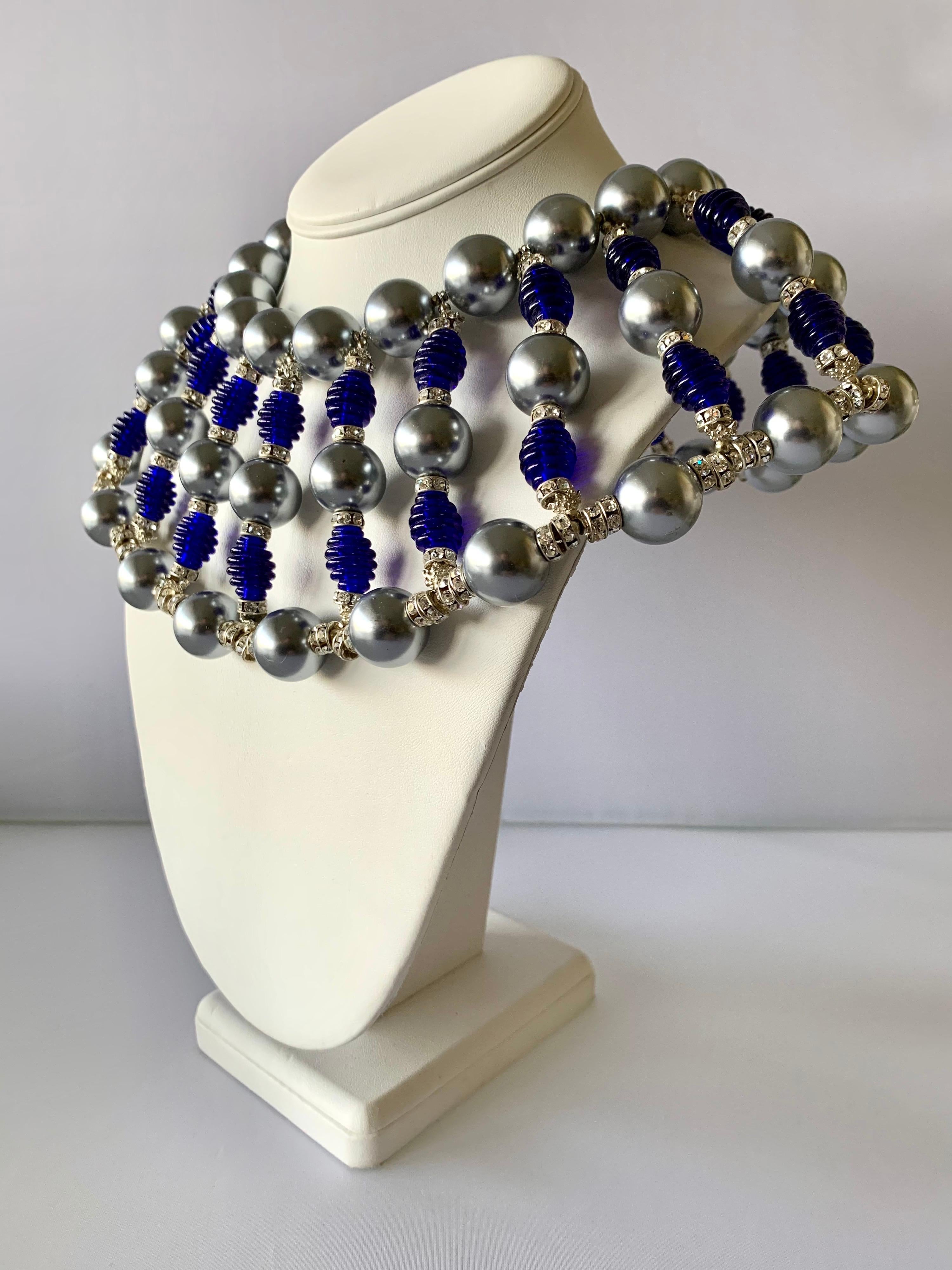 Massive vintage bib statement necklace by Robert F. Clark for William de Lillo. The necklace is comprised out of two rows of large metallic grey pearls and an ornate beaded center Browns of grey pearls, large ribbed cobalt blue beads, and
