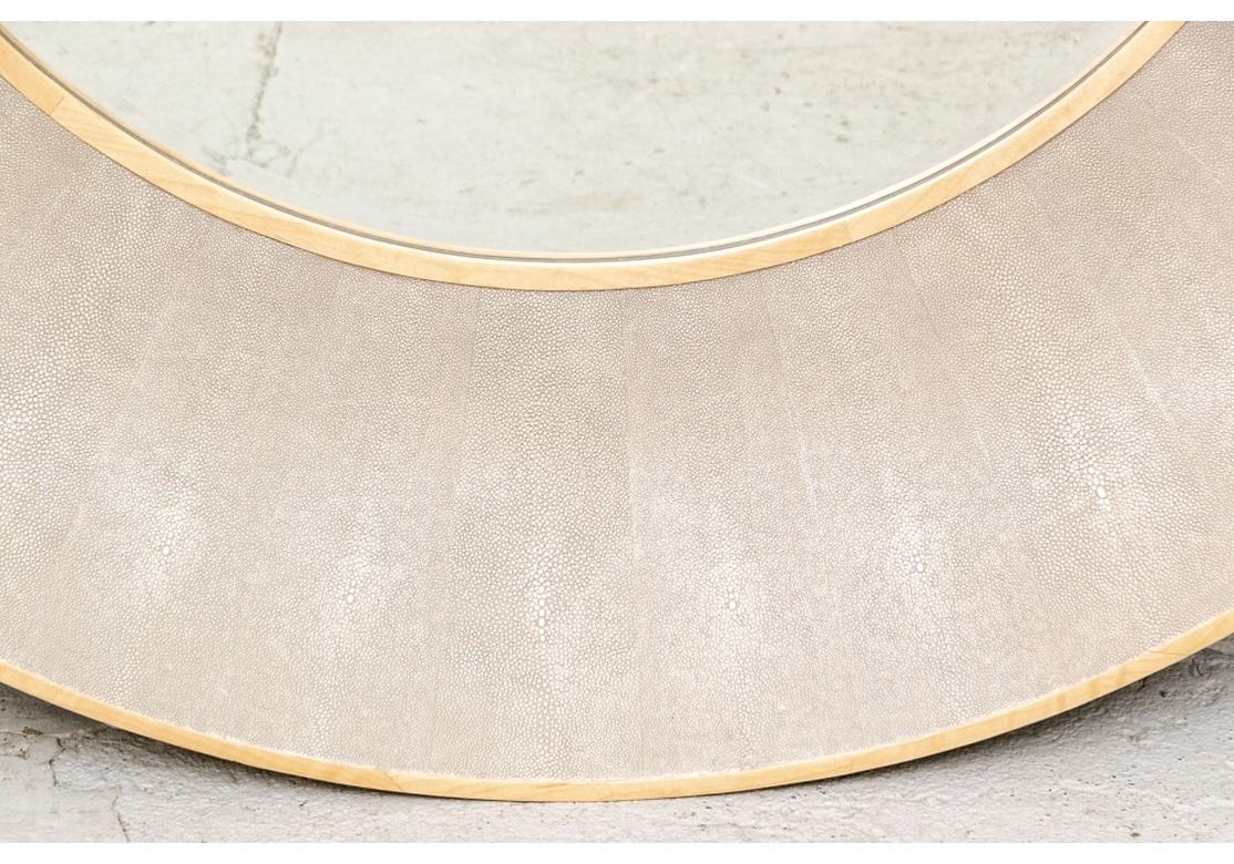 Stylish and very well made Faux Shagreen mirror in the manner of R & Y Augousti. A large scale round mirror with narrow pale wood frames on the outer and inner edges. Deep curved pale gray faux shagreen wide surround. 
Measures: diameter 50